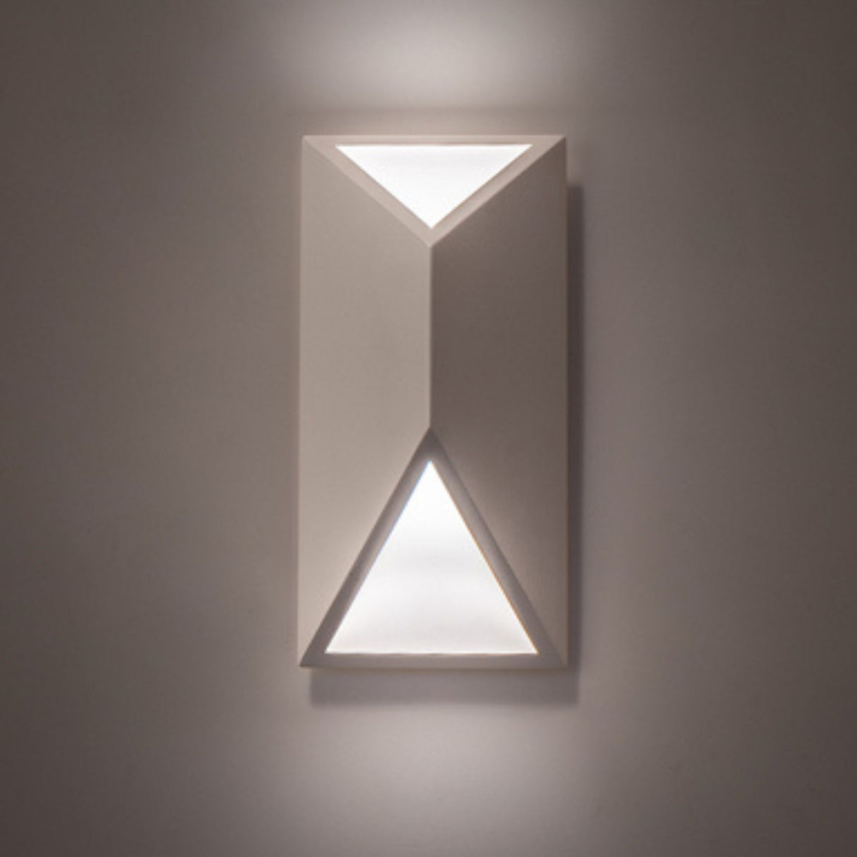 Cillian wall sconce illuminated on a wall, showcasing triangular light patterns.
