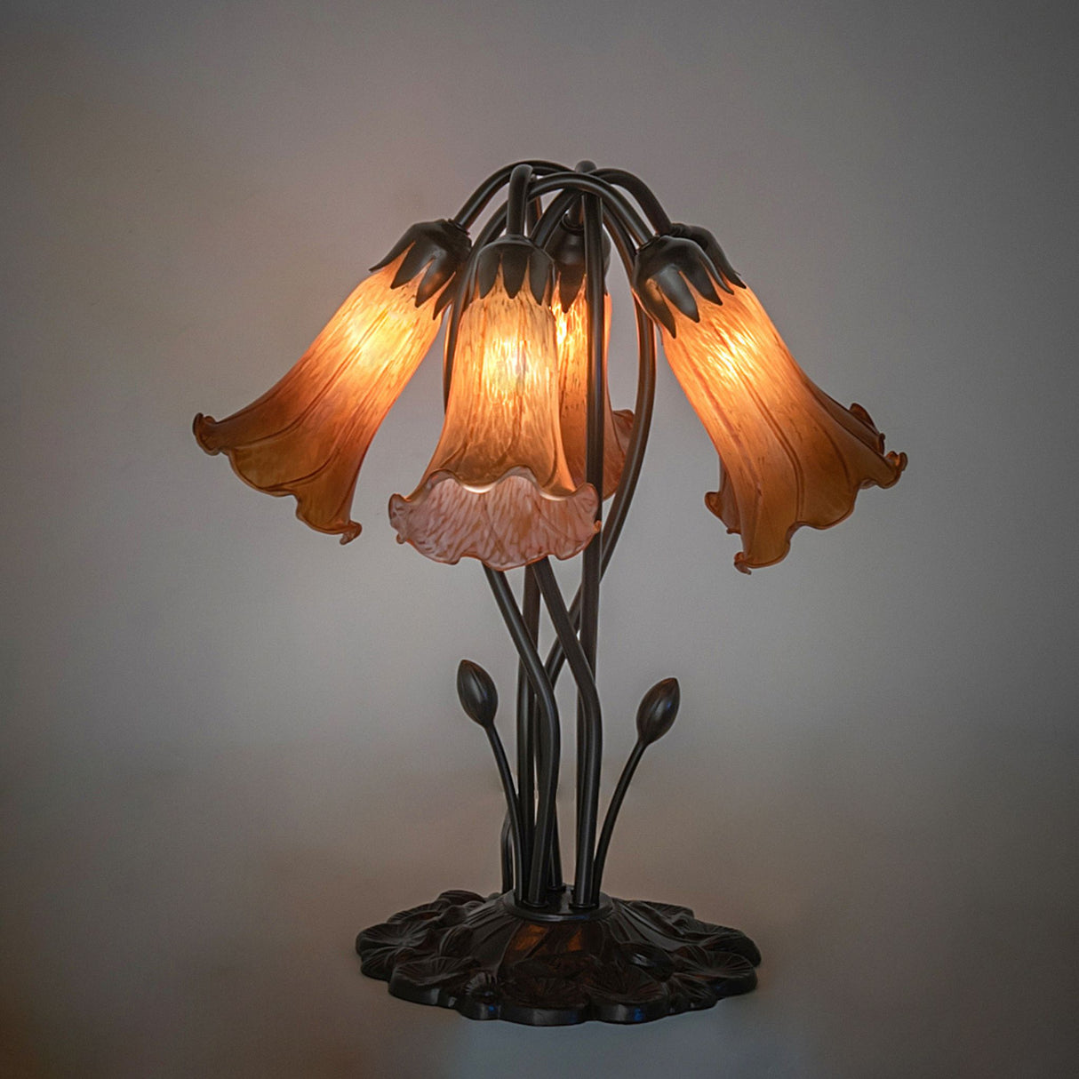 Illuminated amber pond lily table lamp with artistic glass shades.