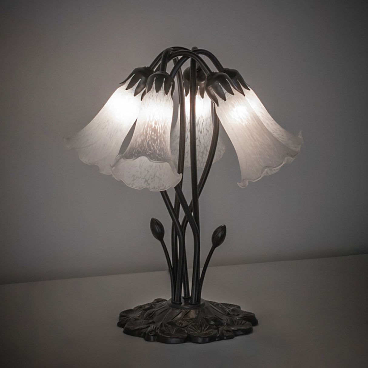 White Tiffany Pond Lily 5 Light Table Lamp with illuminated white glass shades and a floral metal base.
