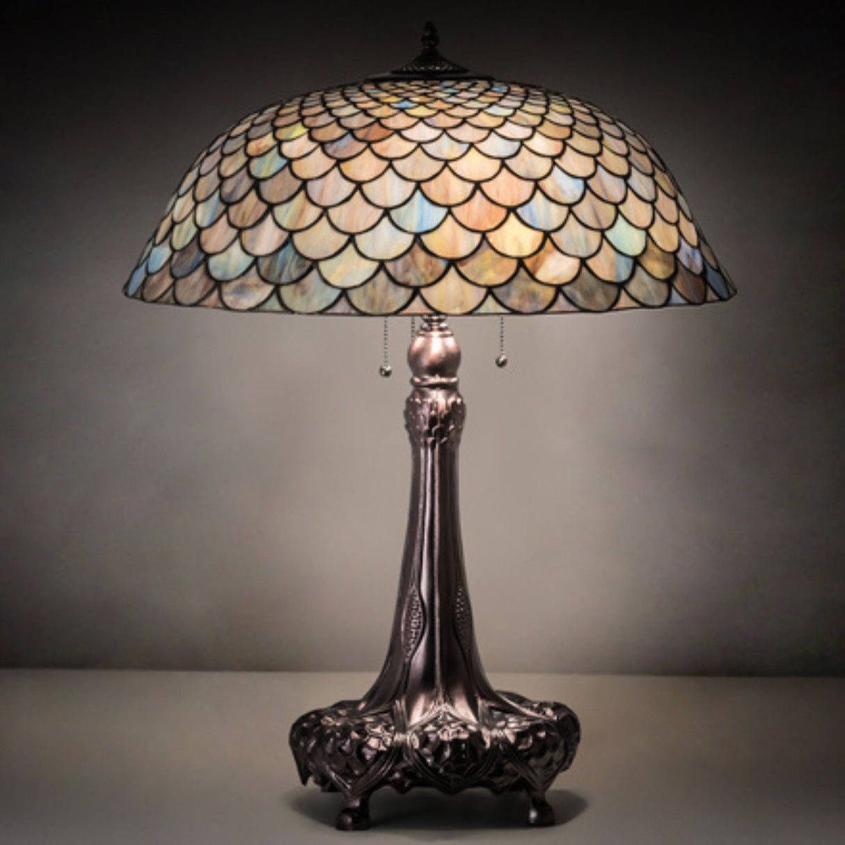 Illuminated 31-inch high Tiffany Fishscale table lamp in a dark setting.