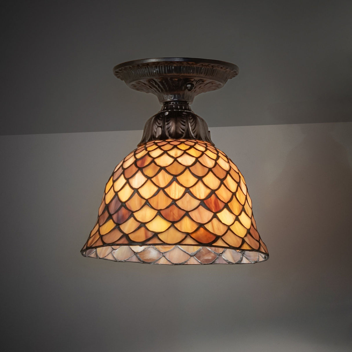 An 8" wide Tiffany glass fishscale semi-flush light fixture that elegantly illuminates the space.
