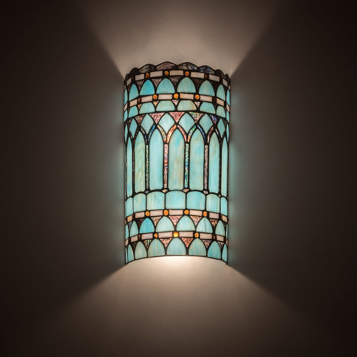 Illuminated front view of the Aello Wall Sconce highlighting its vibrant glass colors.