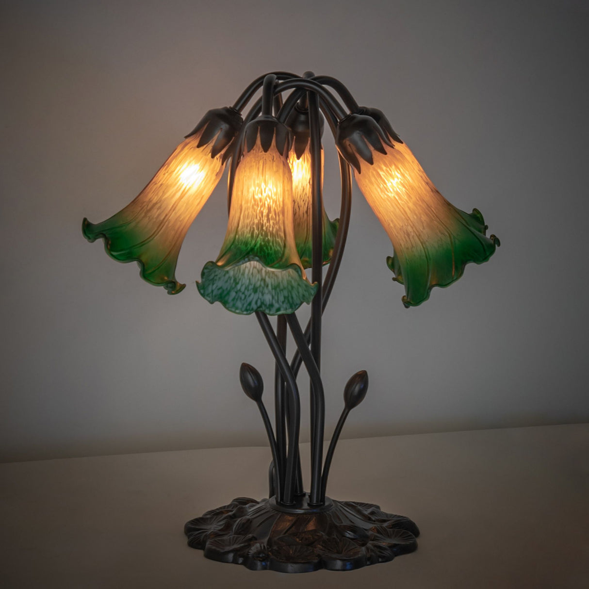 Illuminated amber and green pond lily table lamp with artistic glass shades.