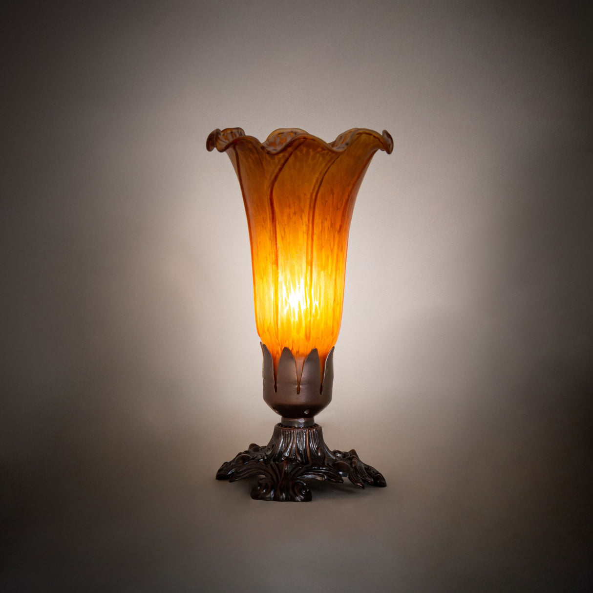 Amber pond lily Victorian mini lamp glowing warmly in a dimly lit setting.