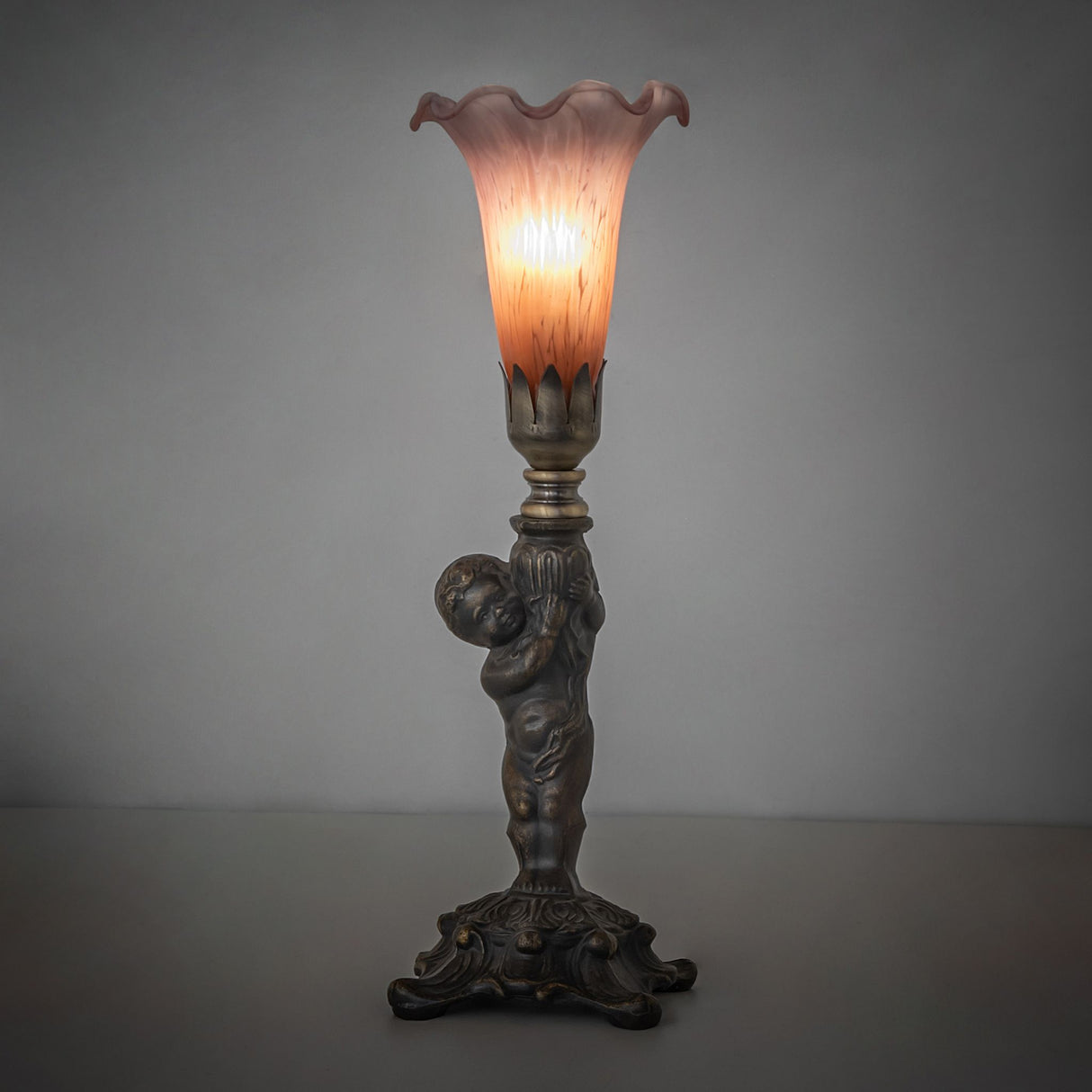 Amber and purple cherub mini lamp illuminated in ambient setting.