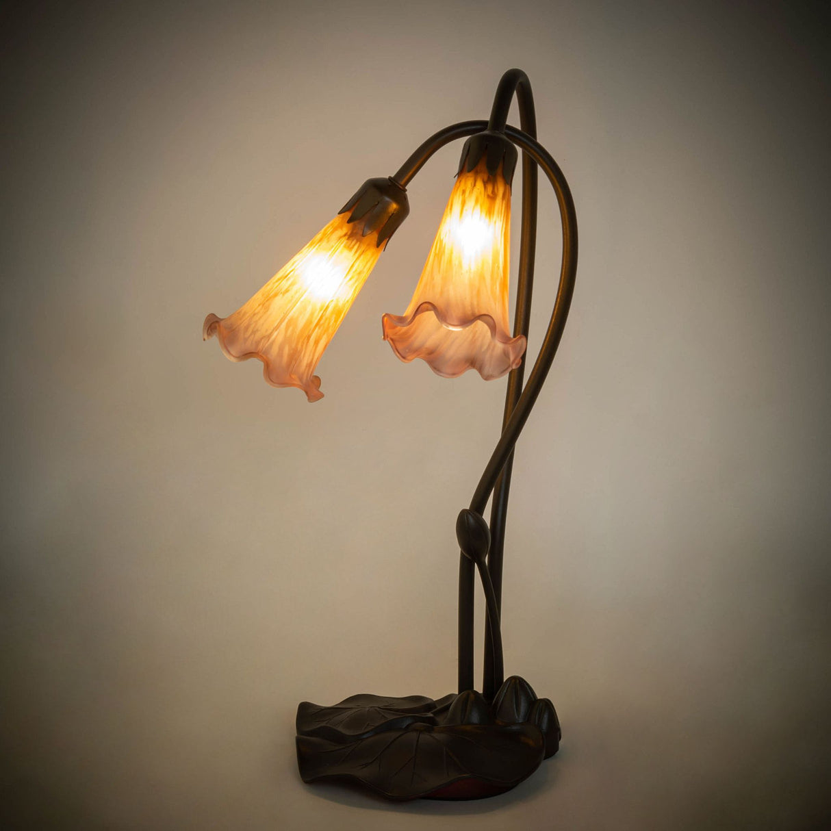 Illuminated view of the Amber/Purple Pond Lily table lamp glowing with warm amber and purple hues.