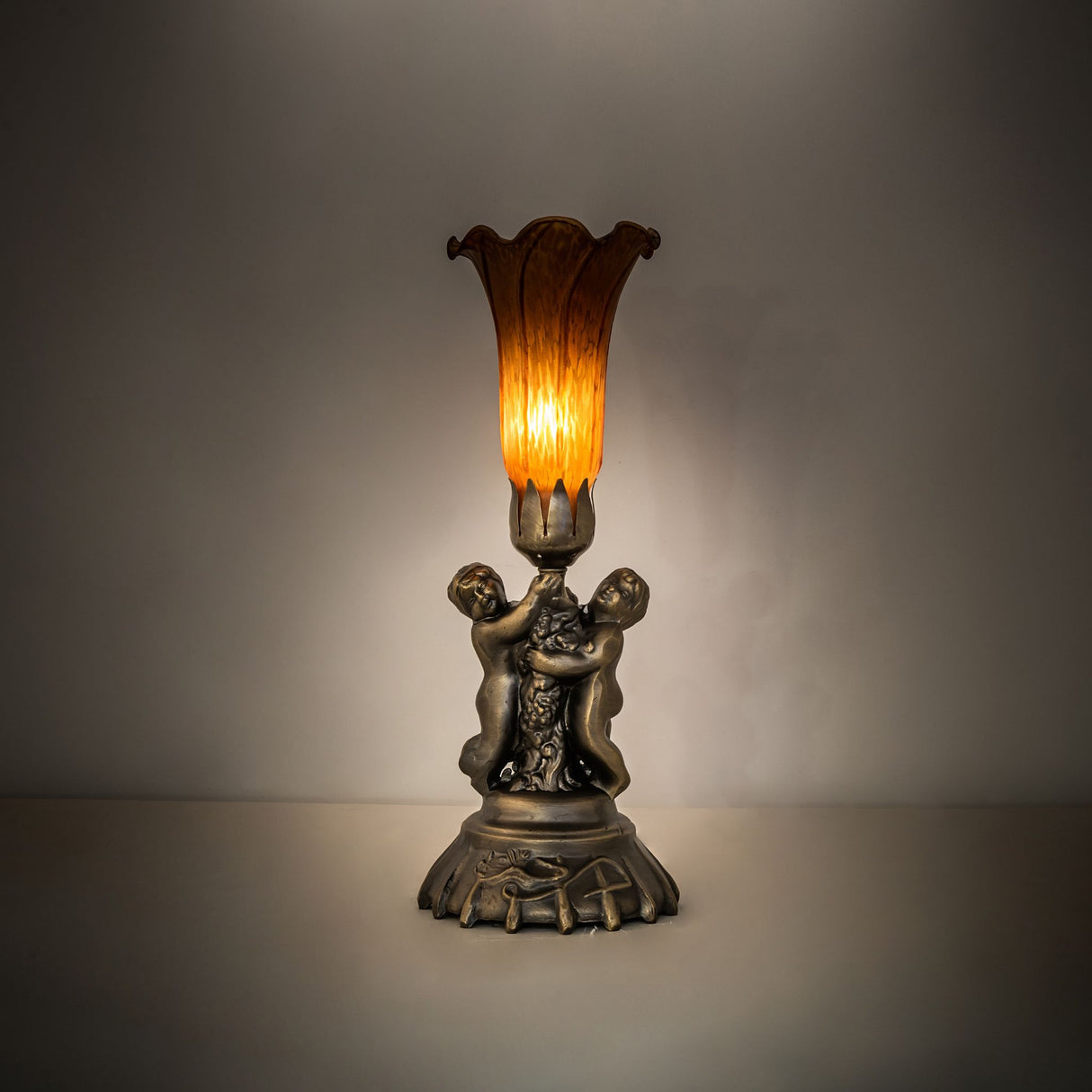 Amber Tiffany-style cherub accent lamp illuminated in ambient setting.