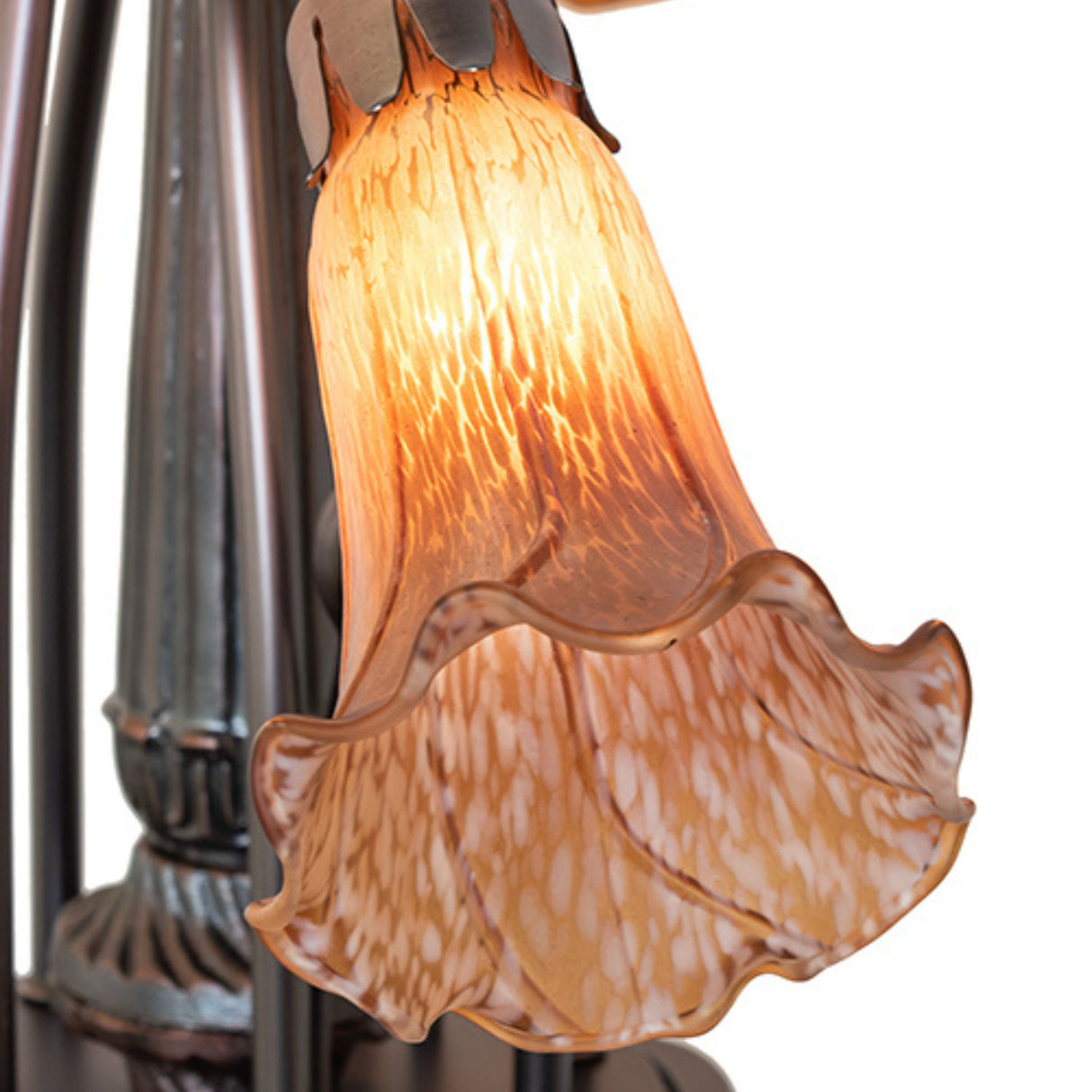 Close-up of amber glass lily shade on Tiffany chandelier with warm light glow