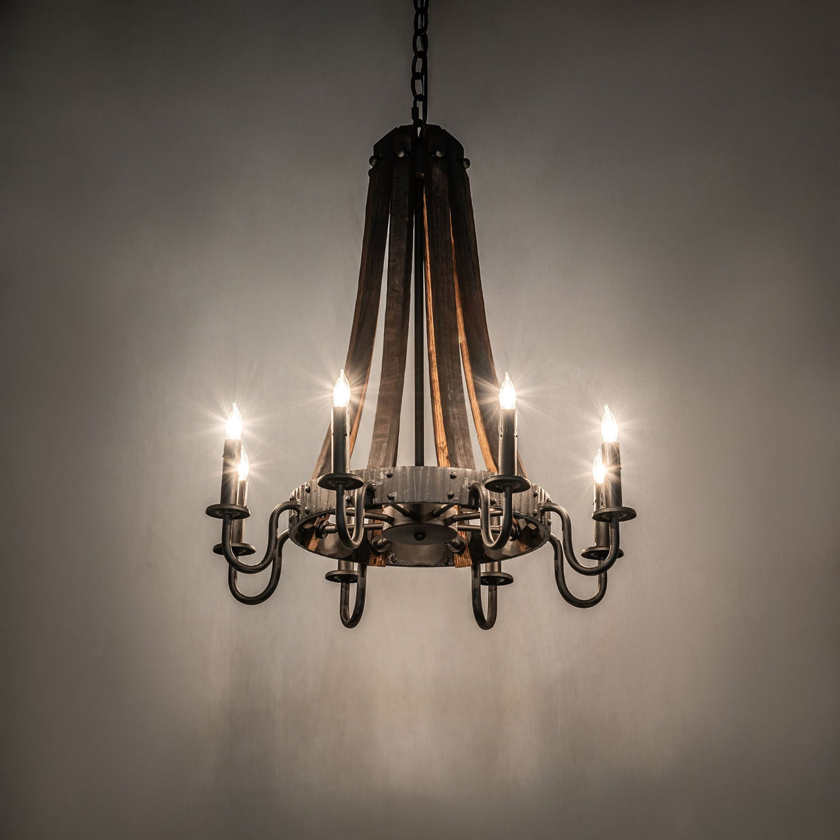 Ambient view of chandelier in dark room setting showing warm rustic glow and wood textures.