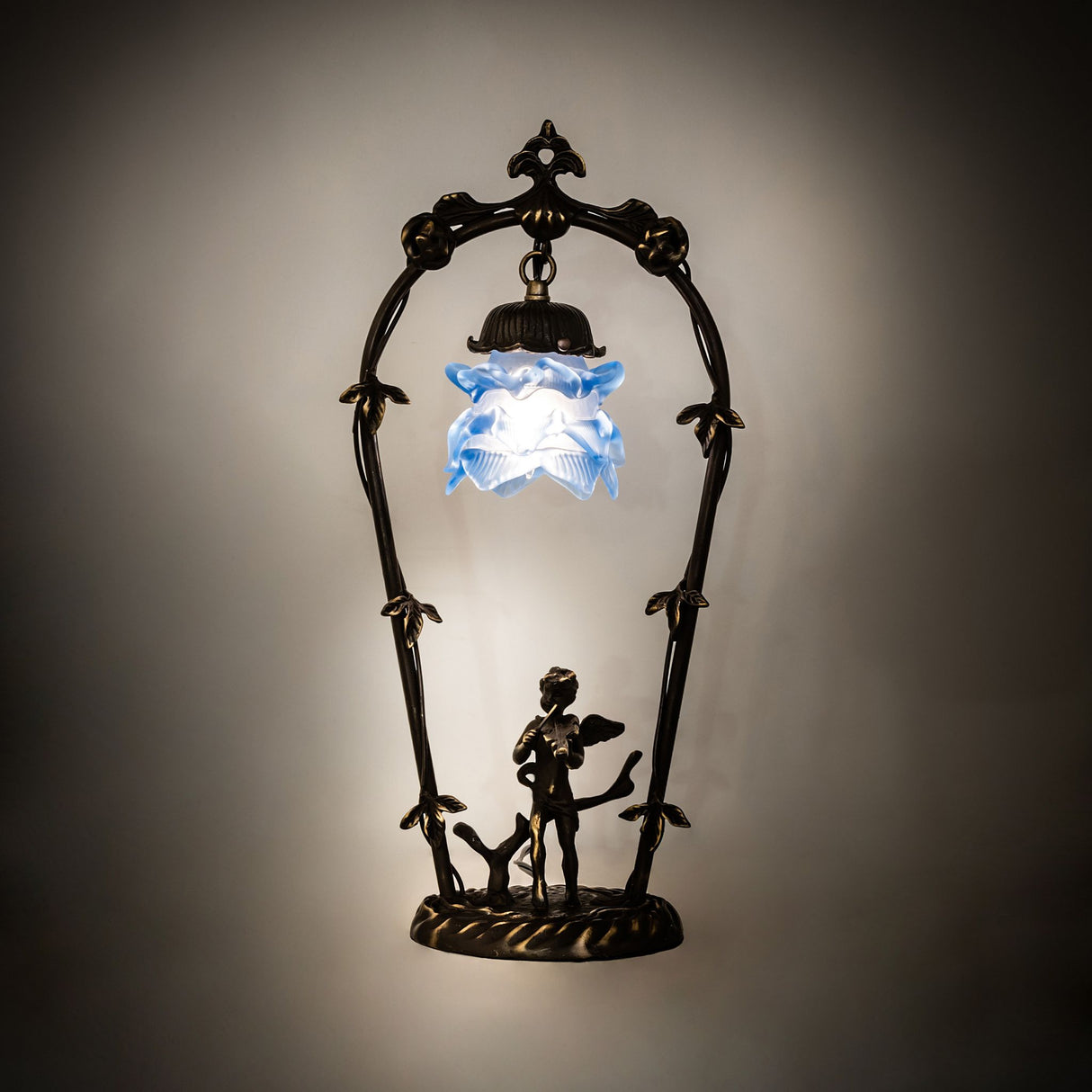 Illuminated view of the cherub mini lamp with a glowing blue ruffled glass shade.