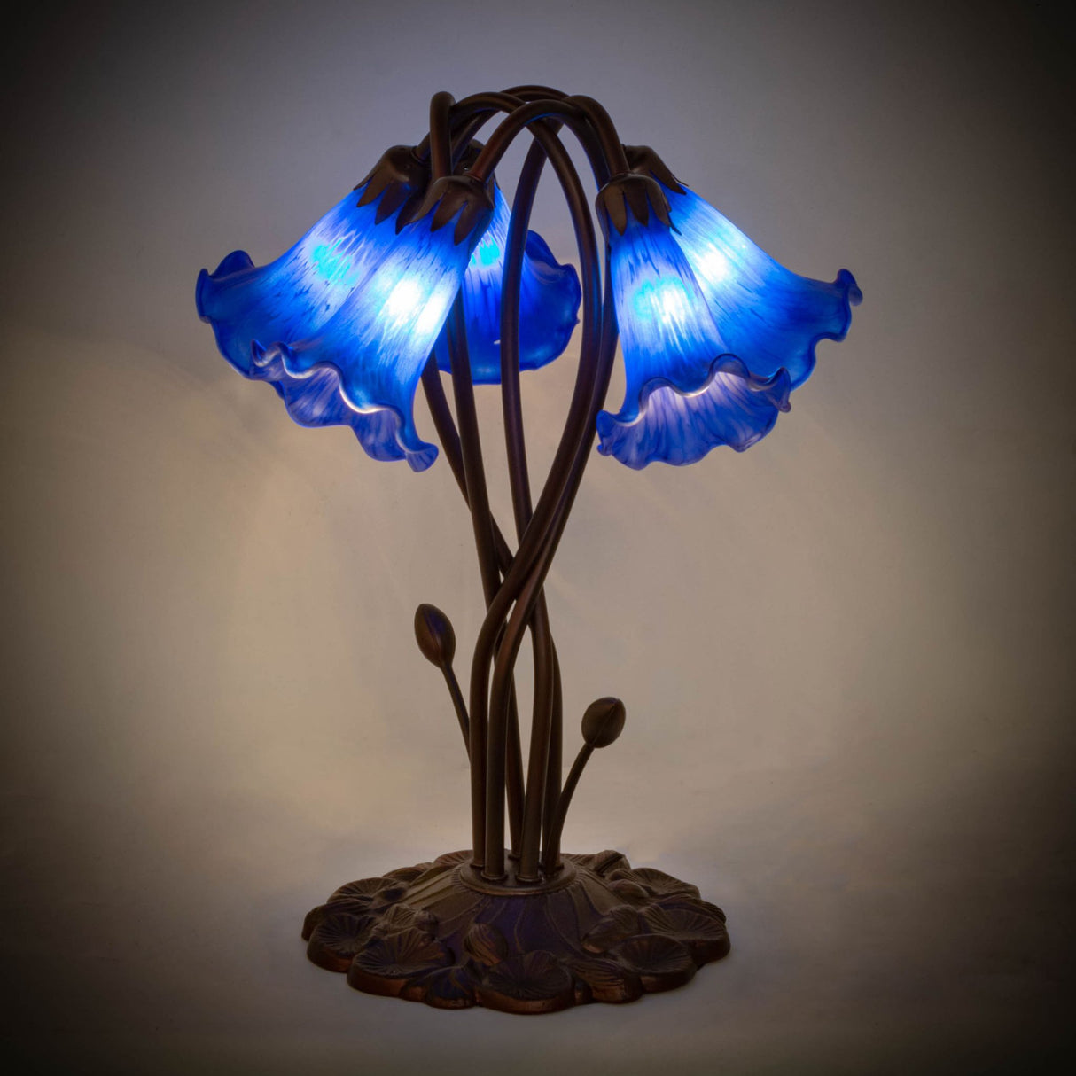 Blue Tiffany lamp glowing warmly in a softly lit setting.
