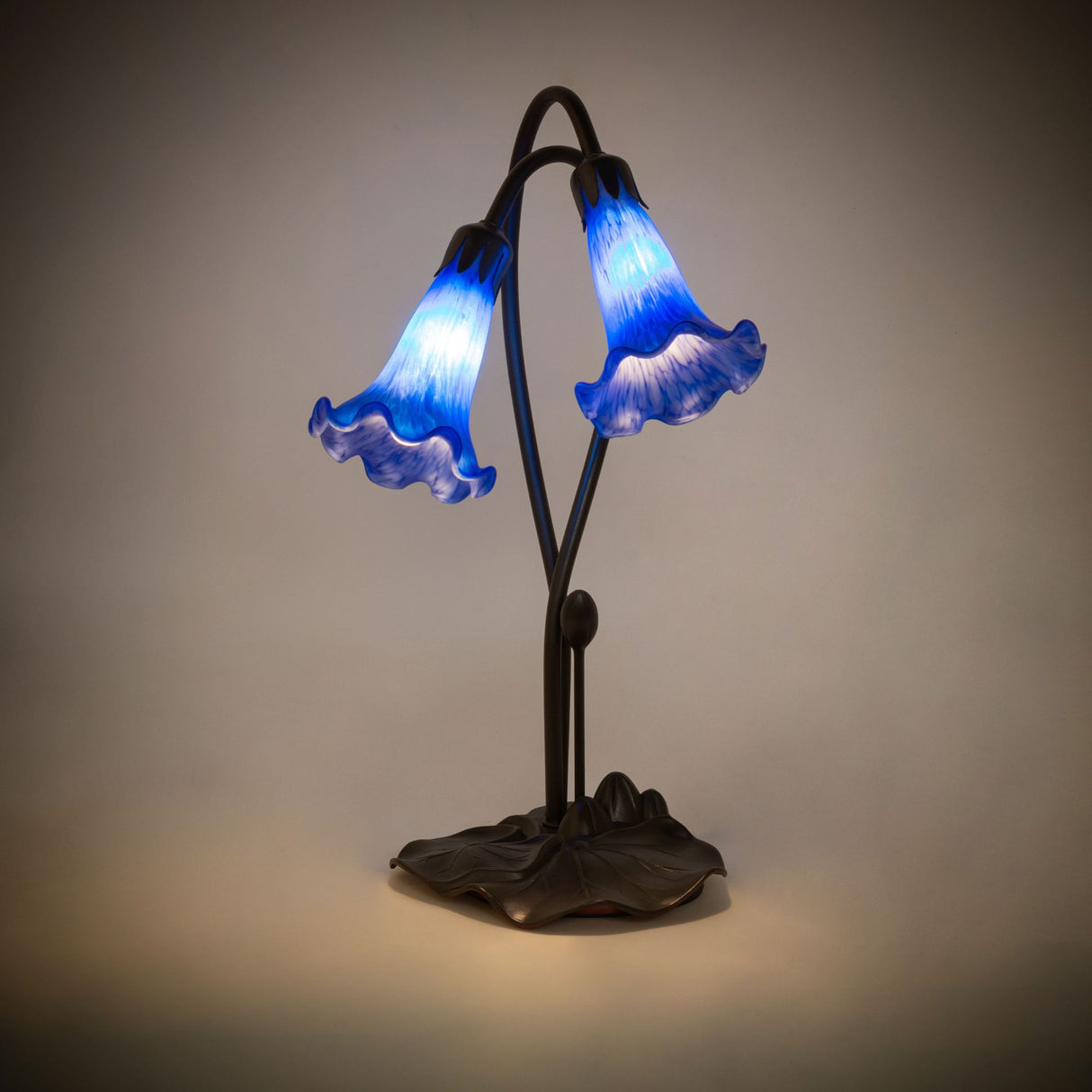 Illuminated view of the Blue Pond Lily accent lamp glowing with soft lavender hues.