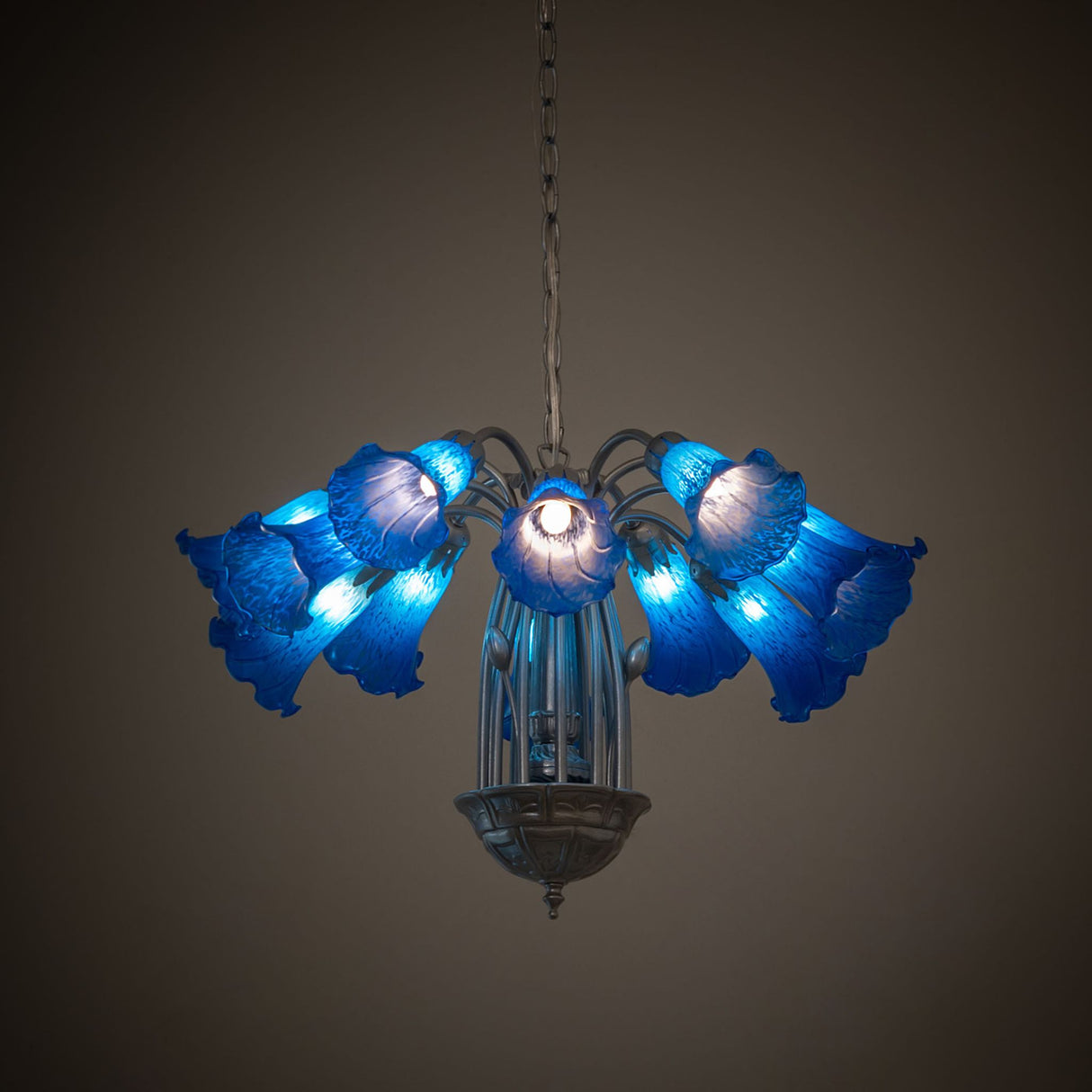 Blue Tiffany Pond Lily 12 light chandelier lit in a dark room setting.