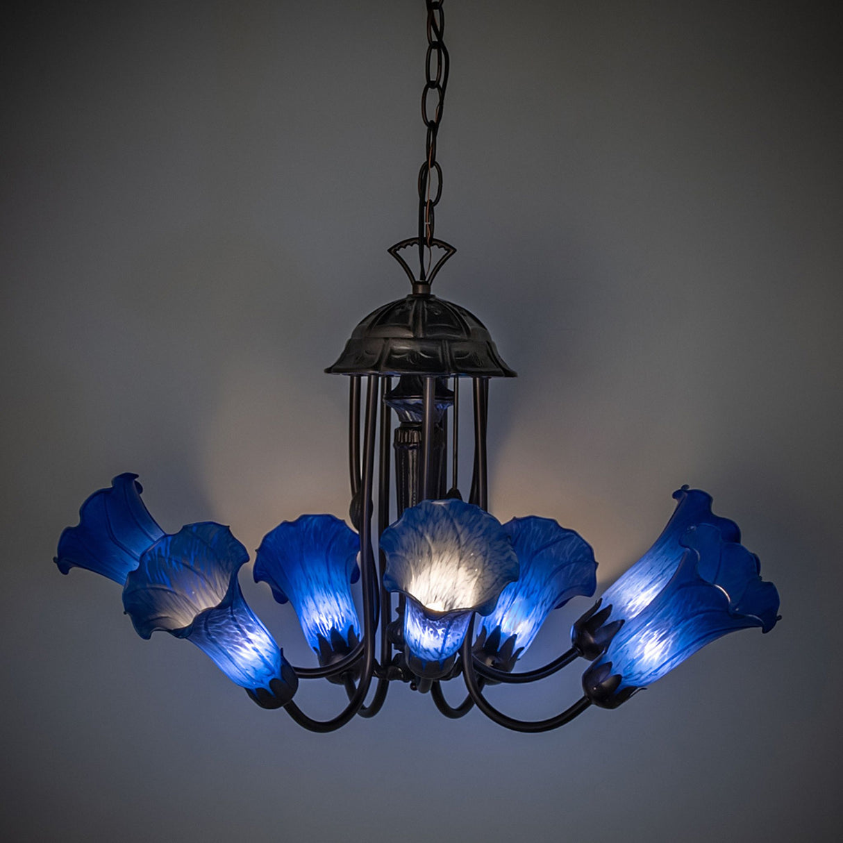 Illuminated view of the Blue Tiffany Pond Lily chandelier casting a warm blue glow.