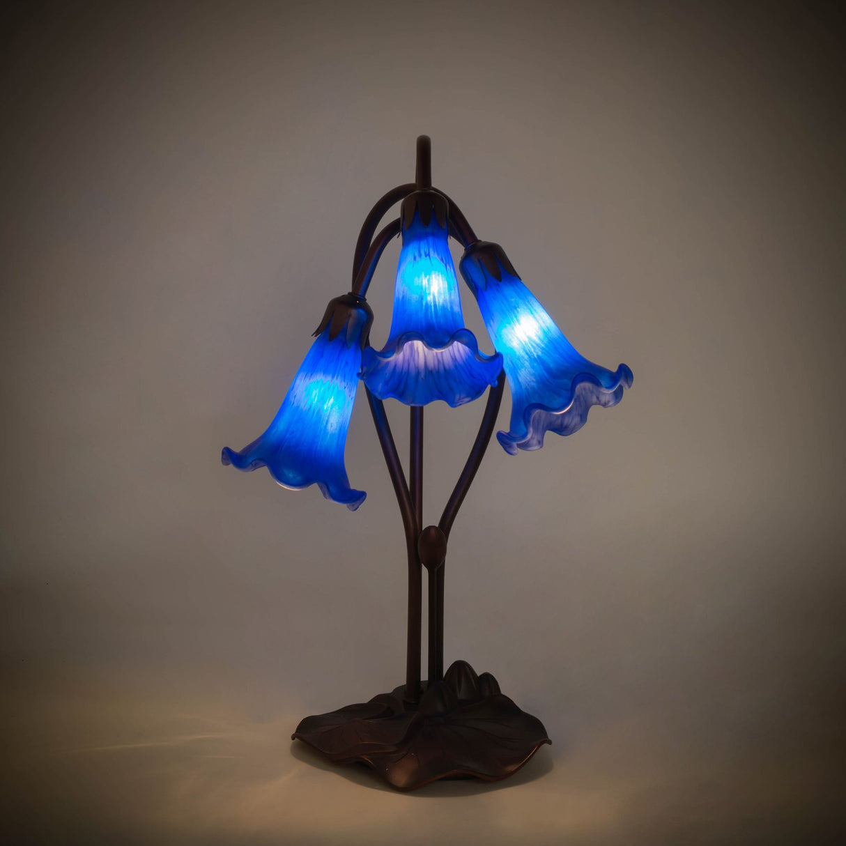 illuminated view of blue tiffany pond lily accent lamp showcasing vibrant indigo glow.