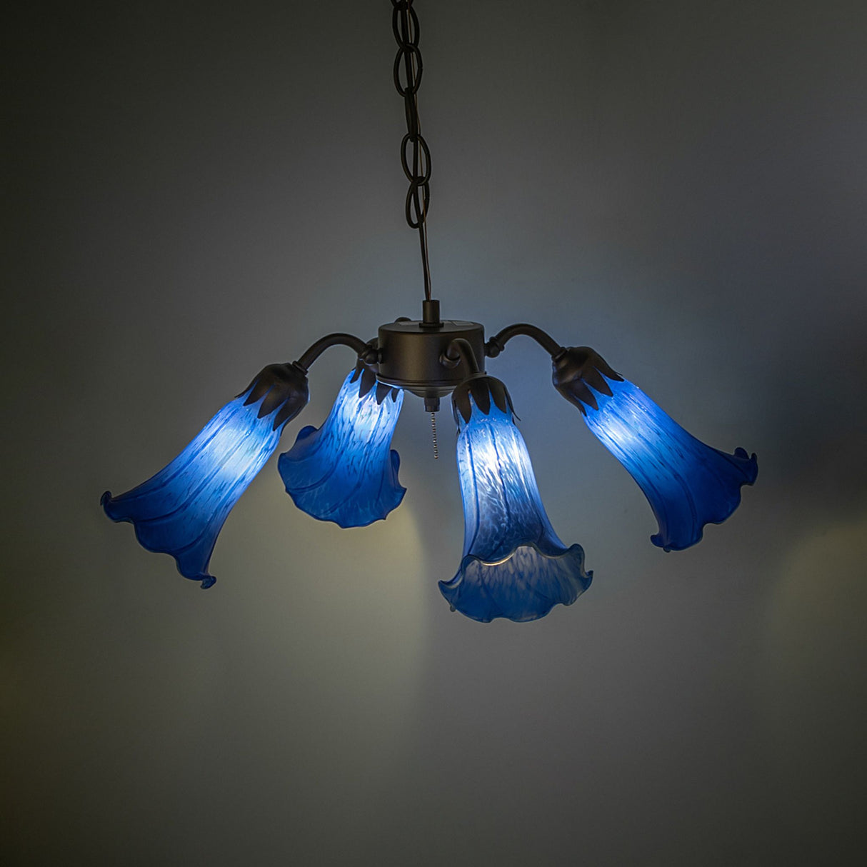 Illuminated Blue Tiffany Pond Lily fan light in a warm setting.
