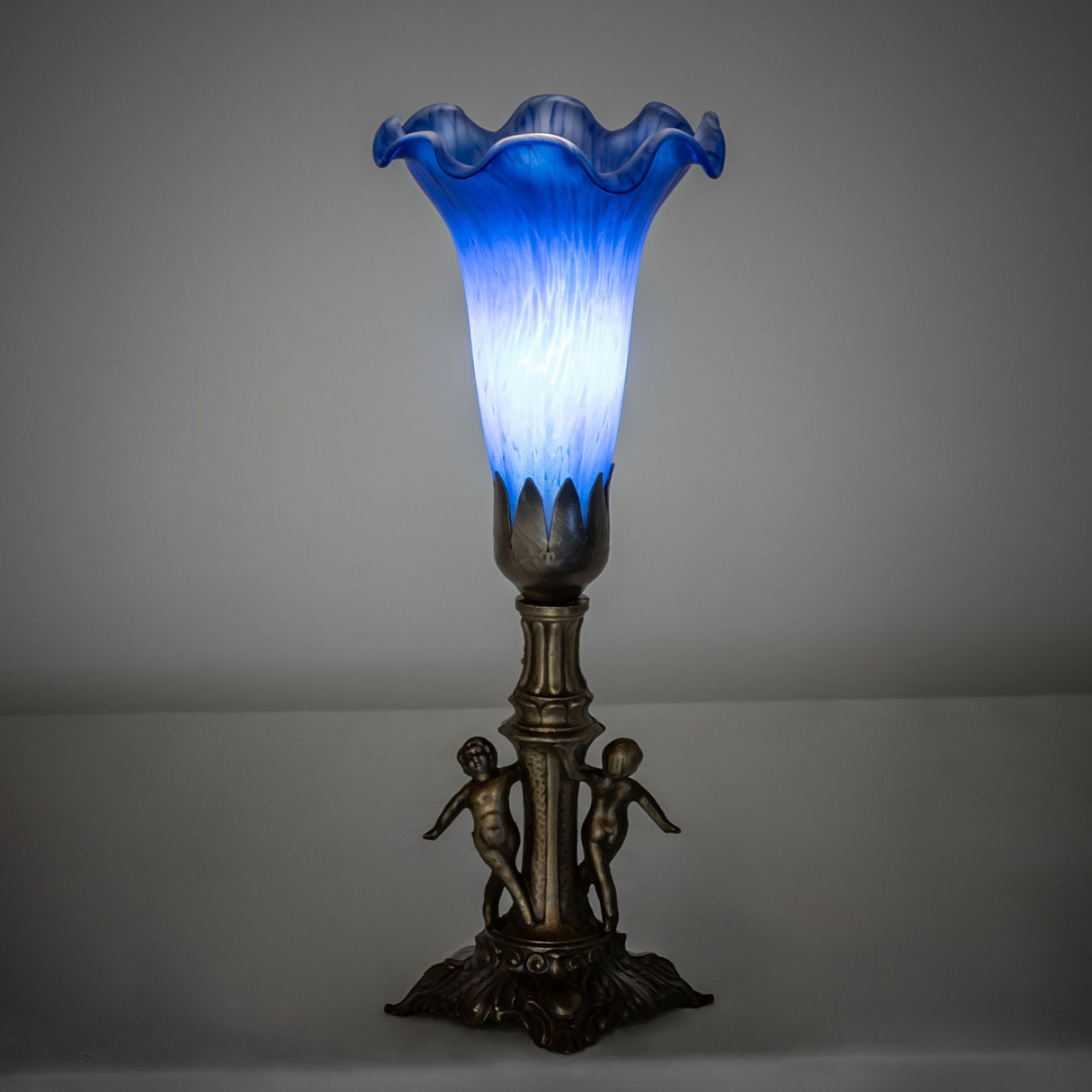 Ambient view of the Blue Tiffany Pond Lily Maidens Mini Lamp casting a soft glow in dark room.