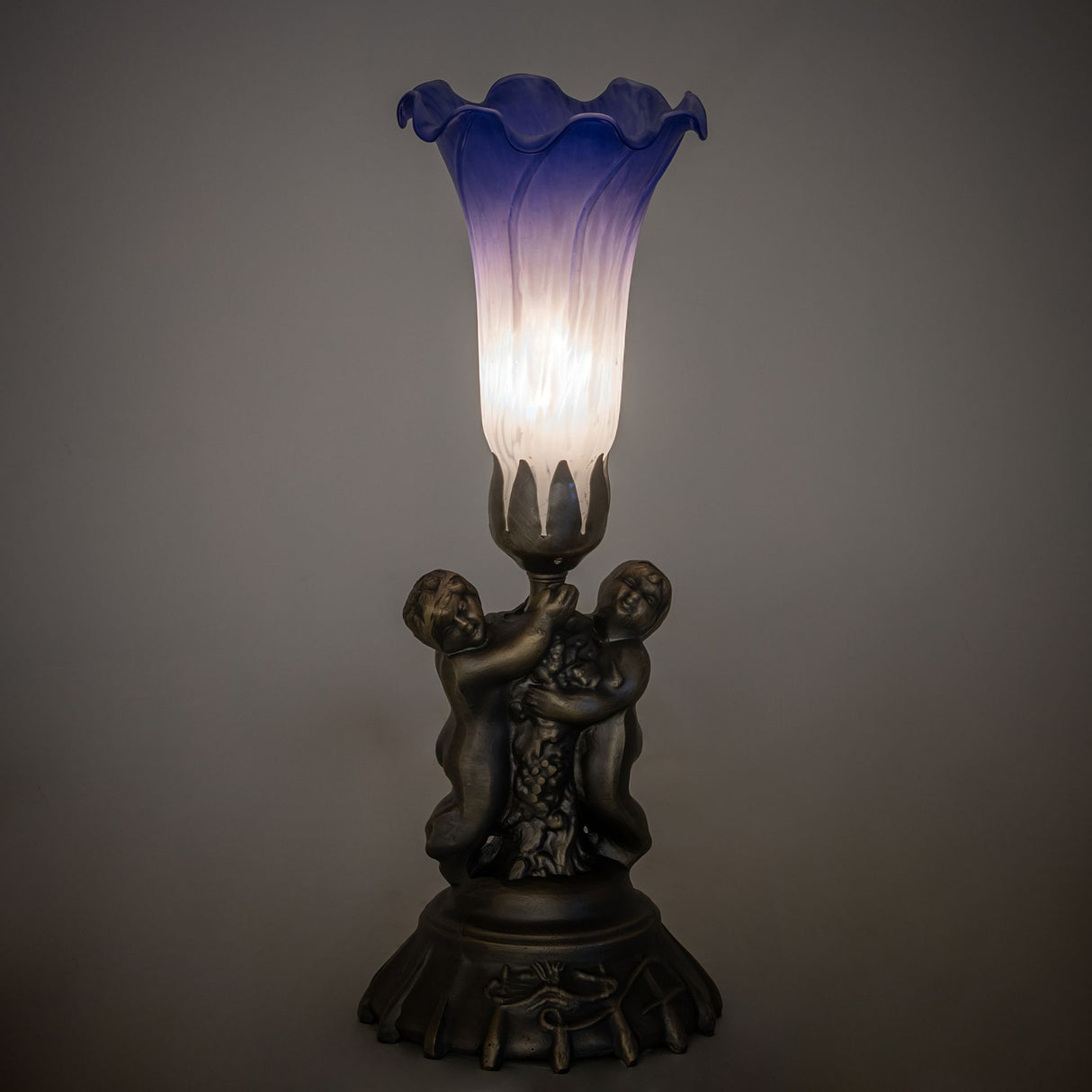 Blue and white cherub accent lamp lit in ambient room setting.