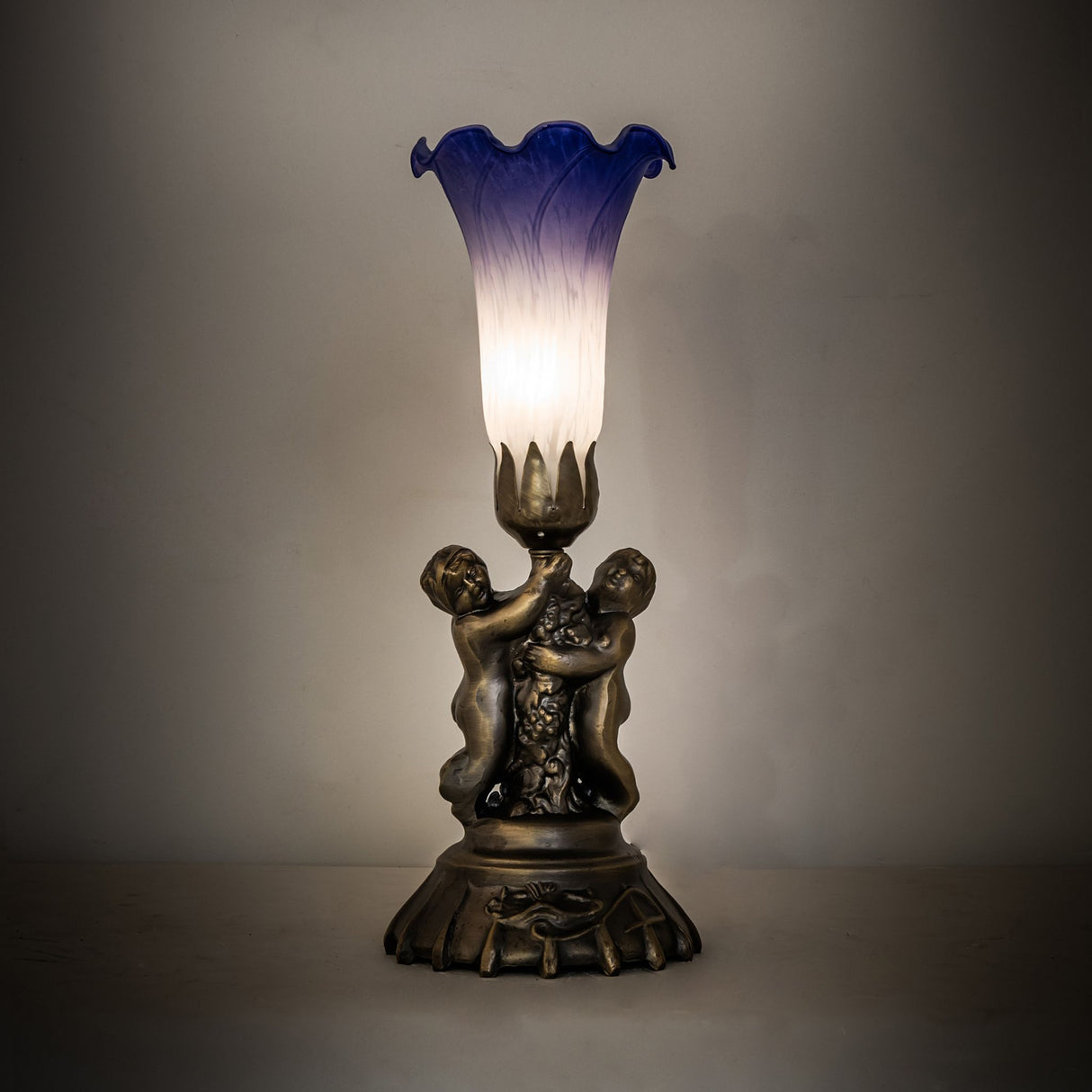 Blue and white pond lily cherub lamp glowing softly in ambient lighting.