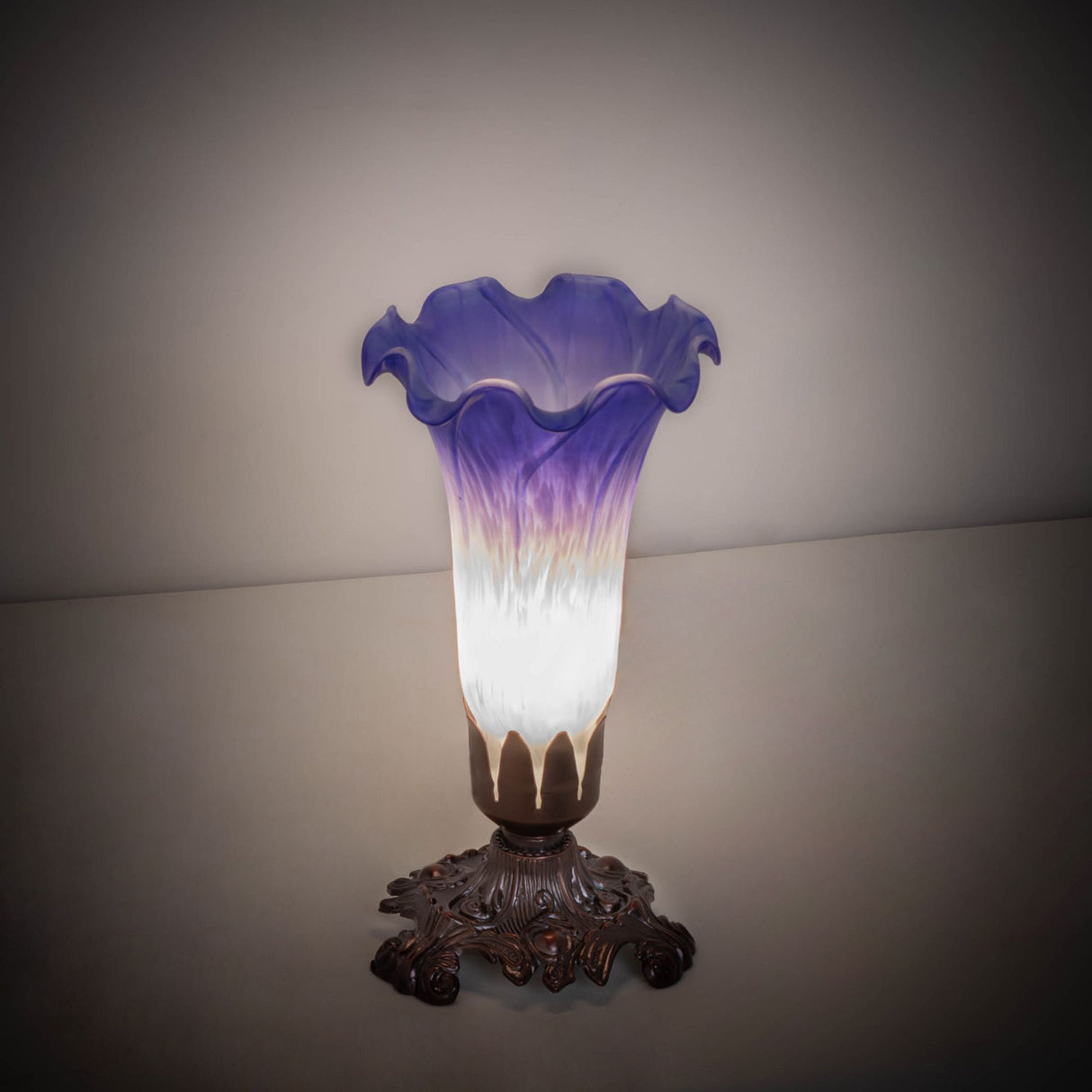 Blue and white Pond Lily mini lamp illuminated in a dim setting.