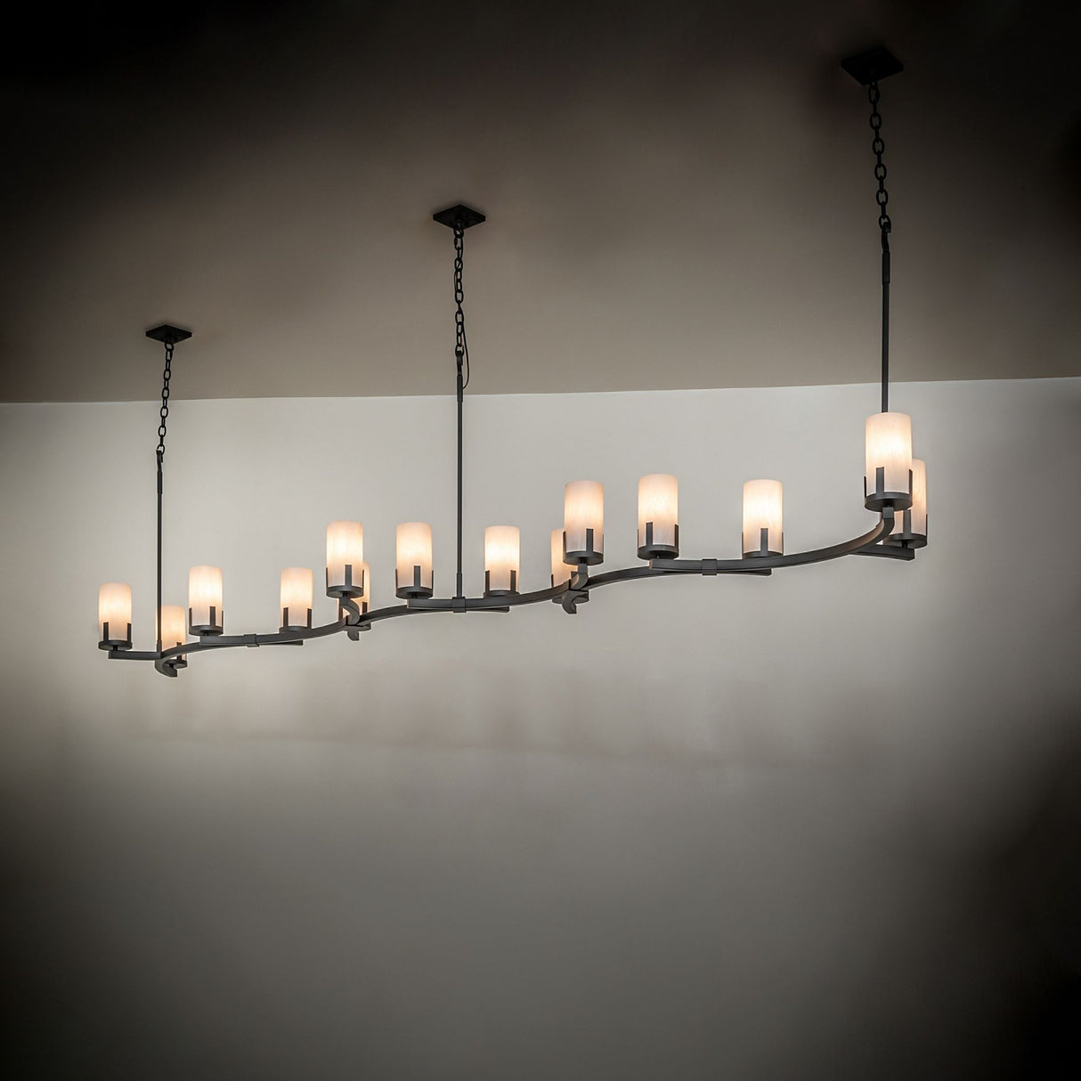 Cero 14-light oblong chandelier installed over dining area with warm ambient illumination.