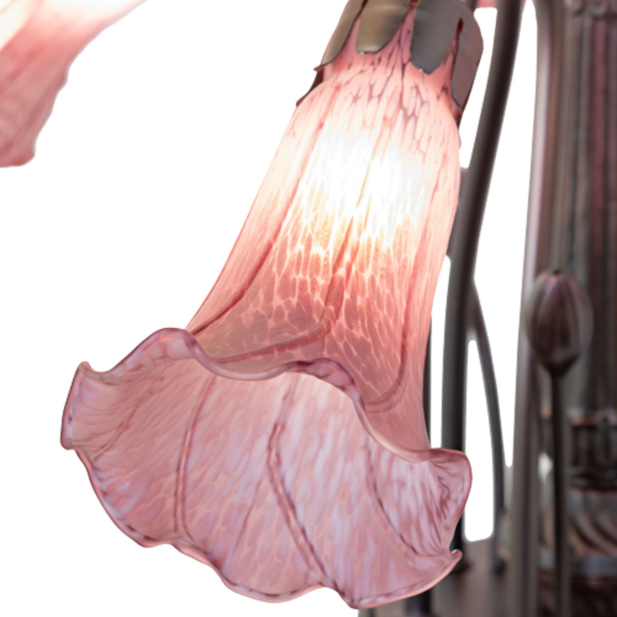 Close-up of a single lavender glass shade in a lily design, glowing softly and attached to a dark metal frame.