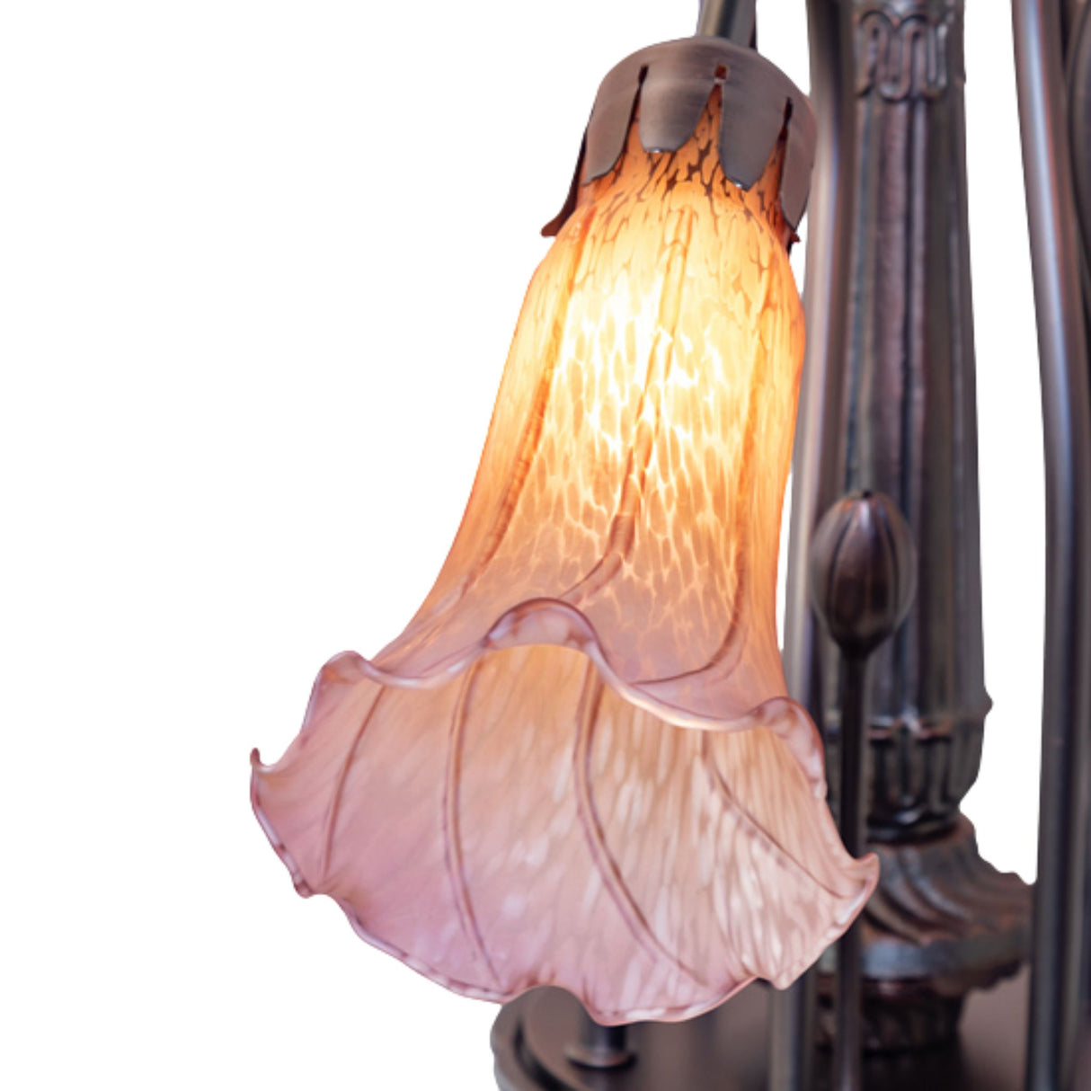 Close-up of a glowing purple Tiffany glass lily shade with intricate details.