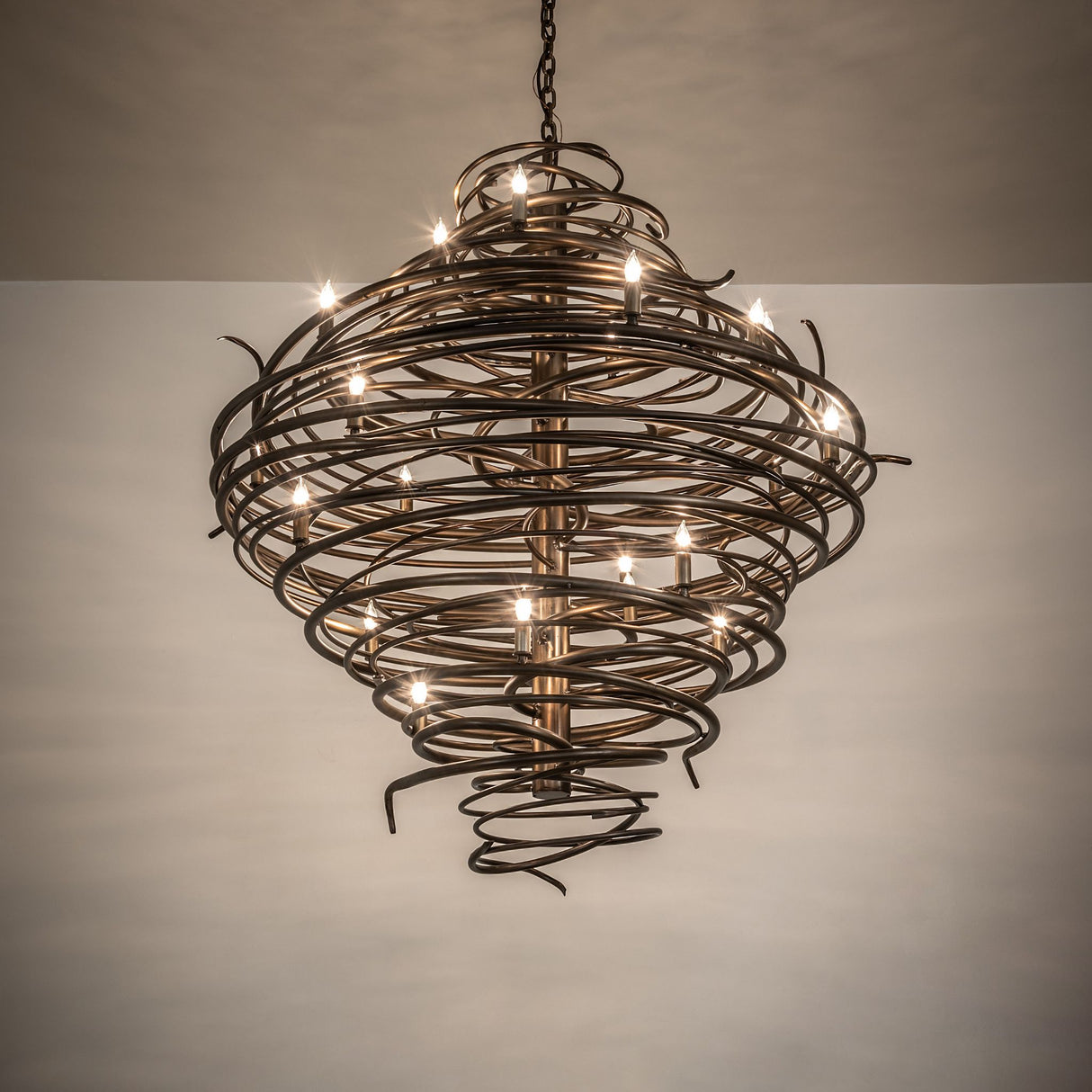 Cyclone chandelier creating warm ambient lighting with sculptural spiral iron design.