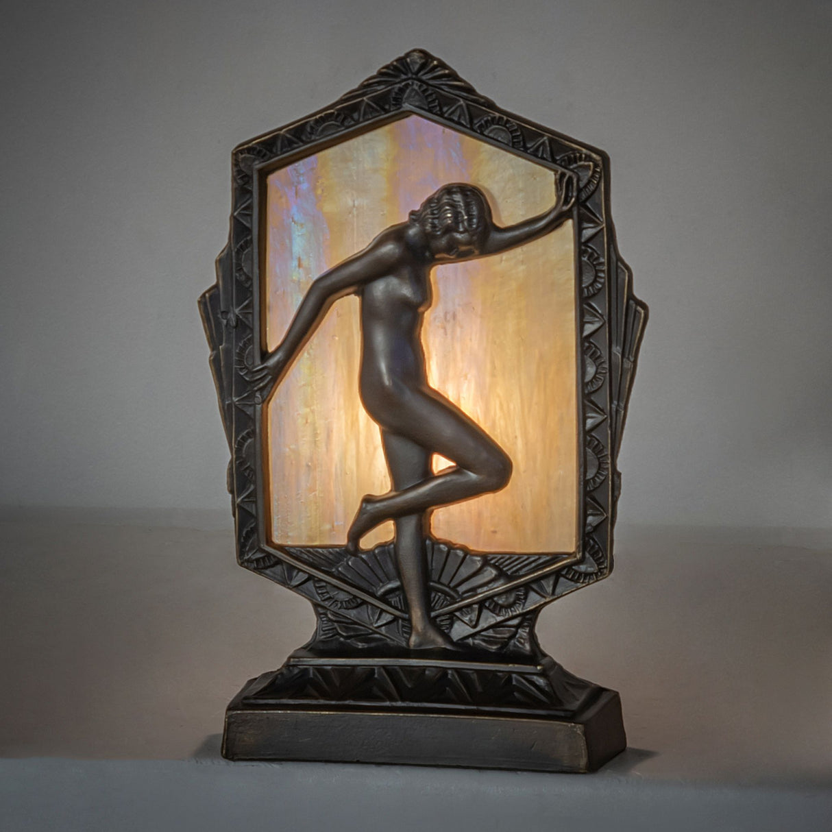Art Deco posing lady accent lamp with a beige iridescent glass panel and antique brass finish.