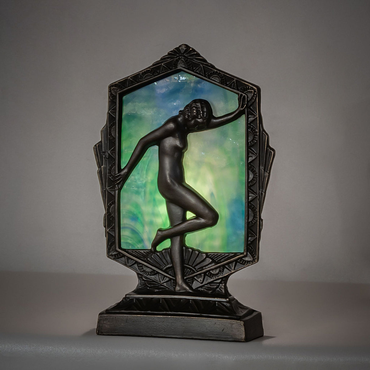 Illuminated Deco Posing Lady accent lamp casting a warm glow through the blue-green glass panel.