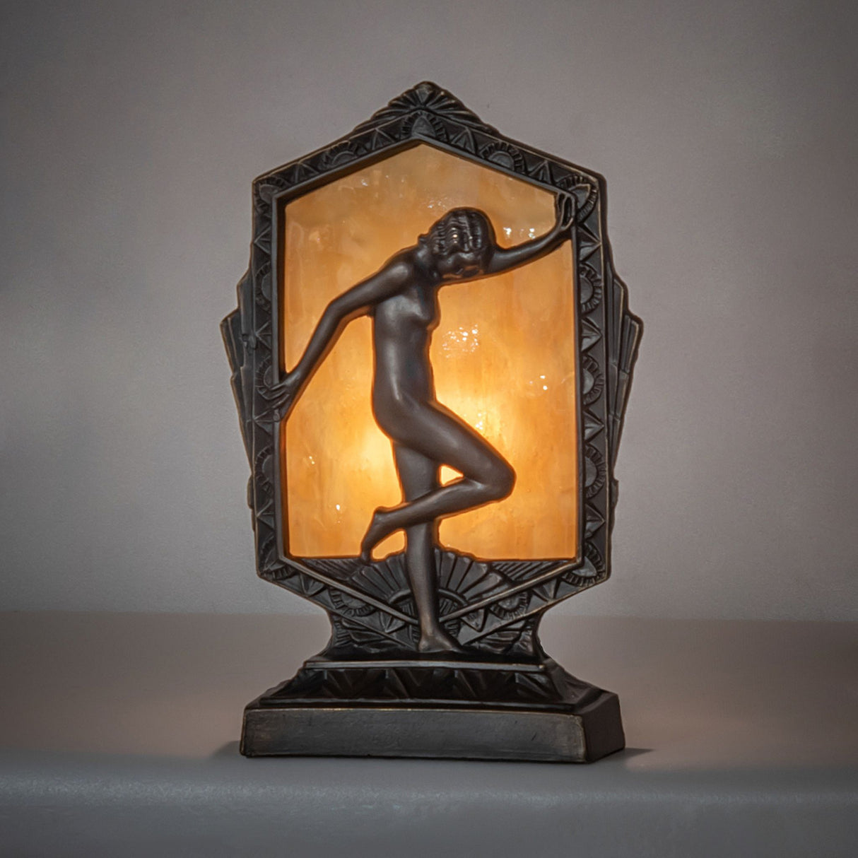 Ambient view of the Deco Posing Lady Accent Lamp, highlighting the soft glow from the beige art glass.