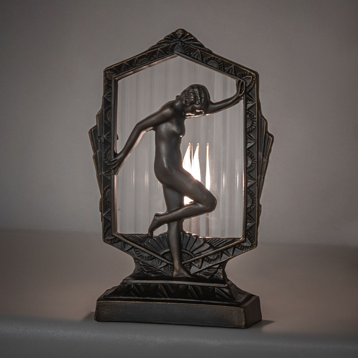 Deco Posing Lady Accent Lamp glowing warmly with clear fluted glass and elegant design.