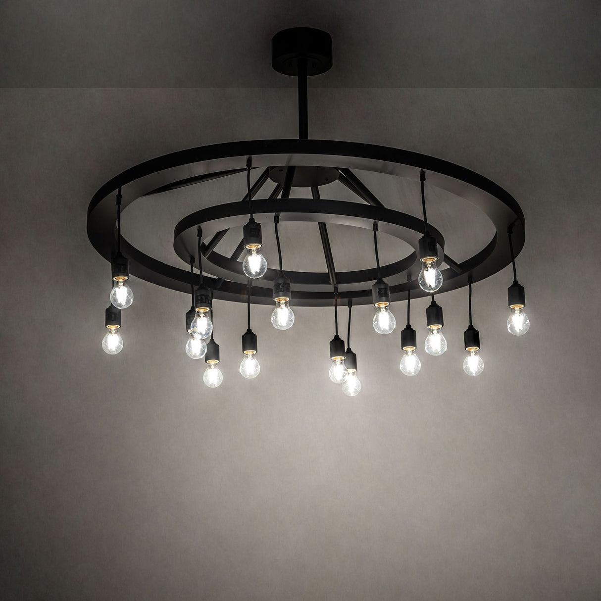 Donner 16 light chandelier shown illuminated in ambient interior setting.