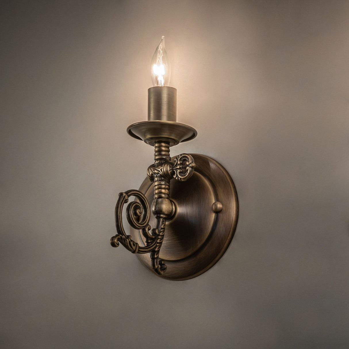 Ambient view of antique brass wall sconce casting warm glow.