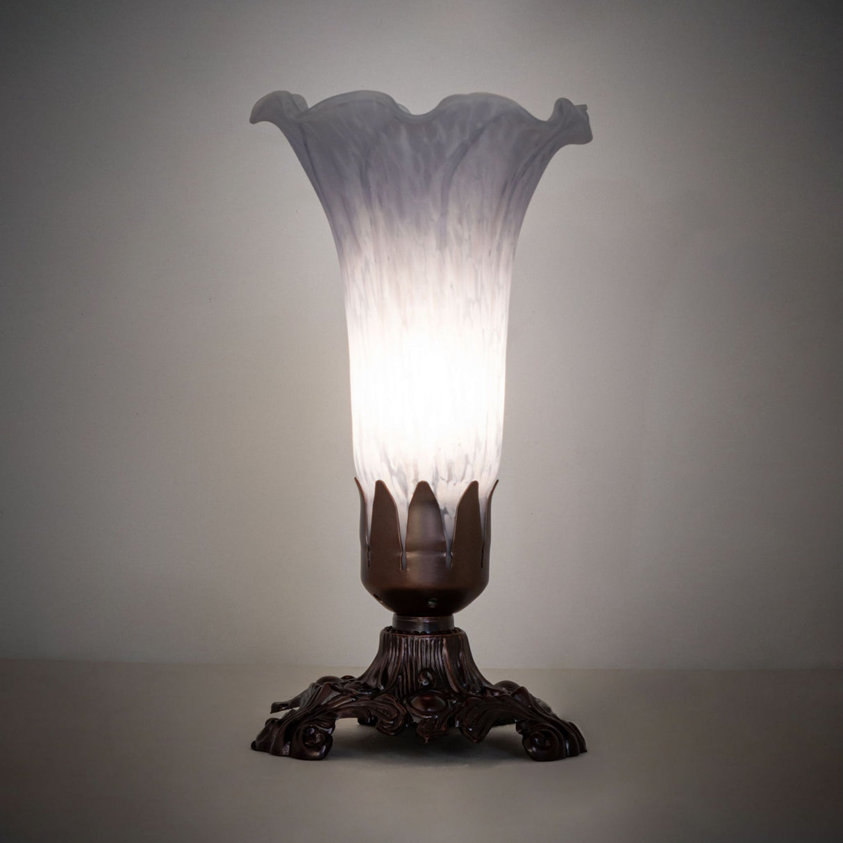 Gray Tiffany Pond Lily Accent Lamp glowing softly in a dimly lit setting.
