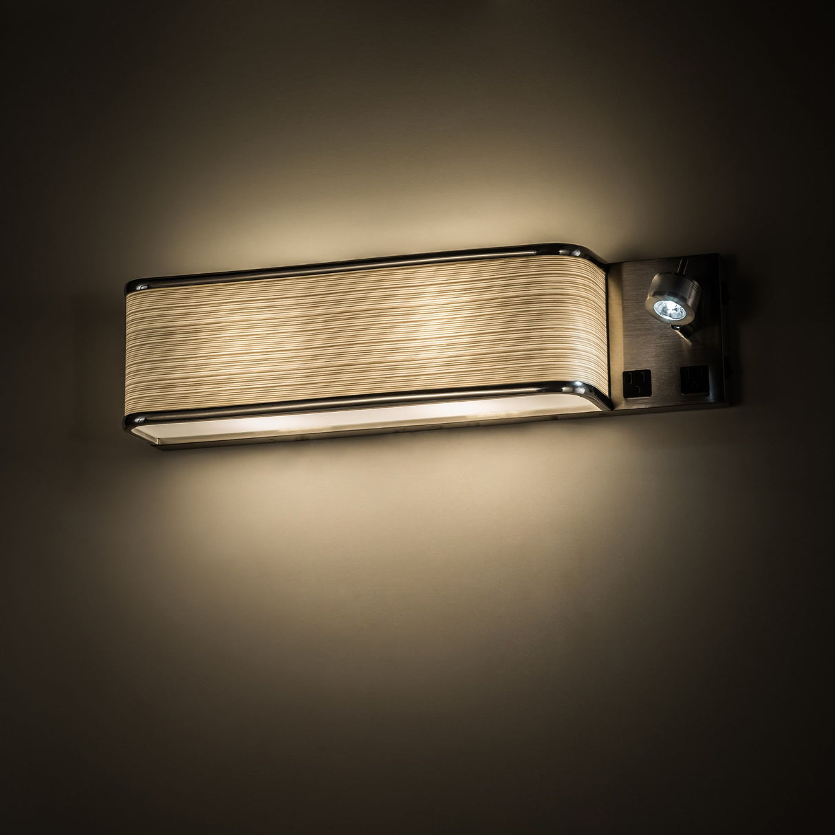 Illuminated Finley wall sconce on a dark wall, highlighting its warm lighting effect.