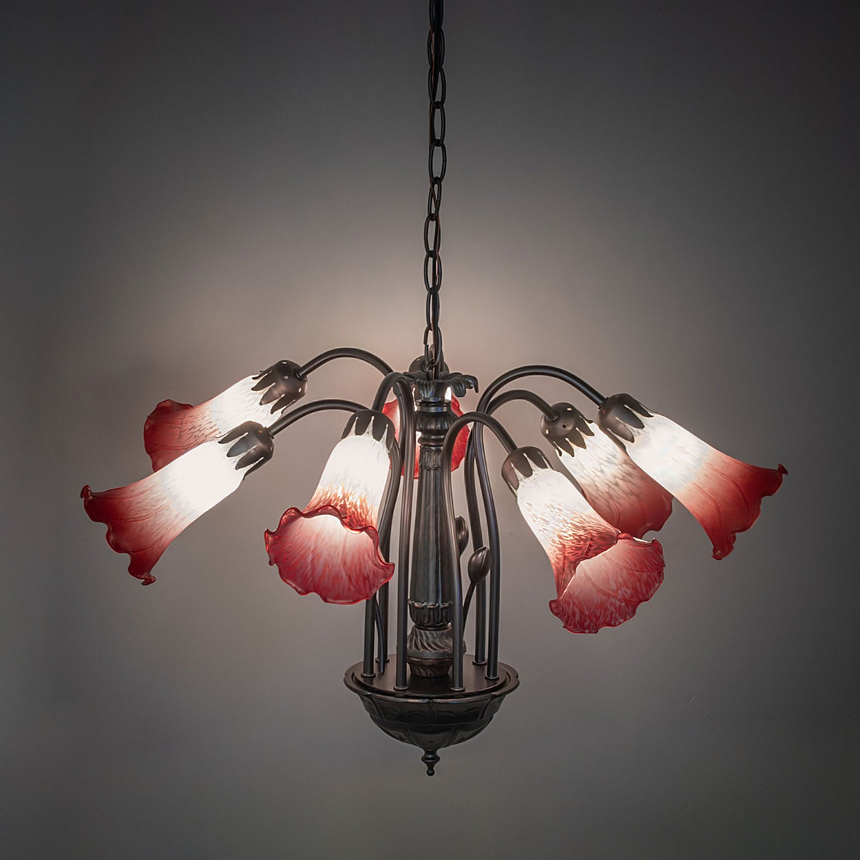 Illuminated pink and white Tiffany chandelier in a dark room.