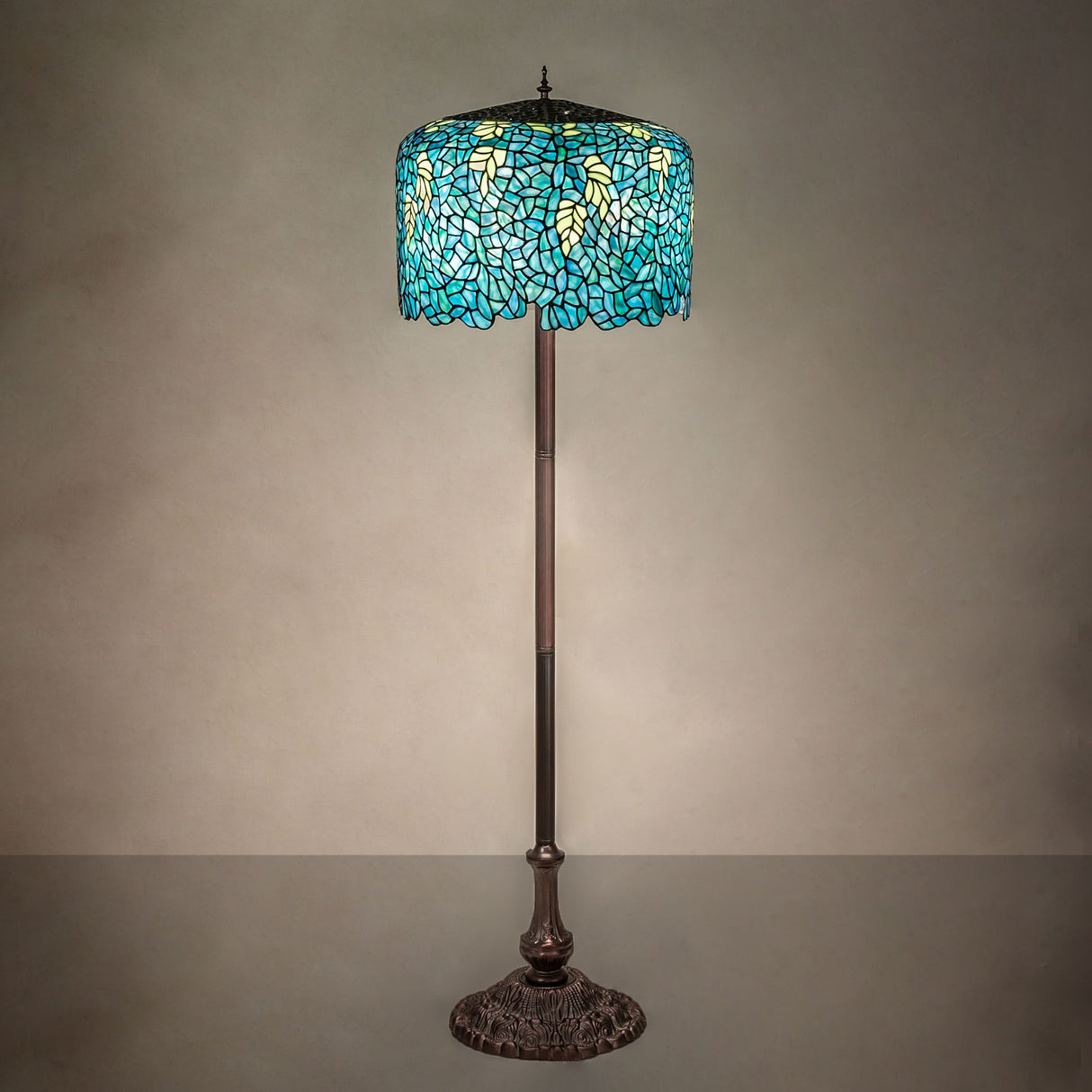 Illuminated Tiffany Wisteria floor lamp casting a warm glow with intricate glass design.