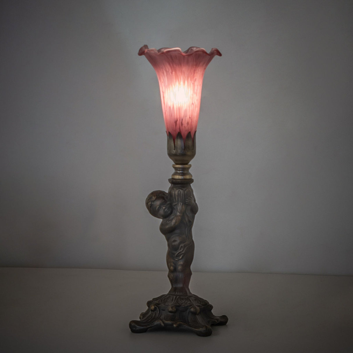 Ambient view of lavender Tiffany-style mini lamp with cherub figure.