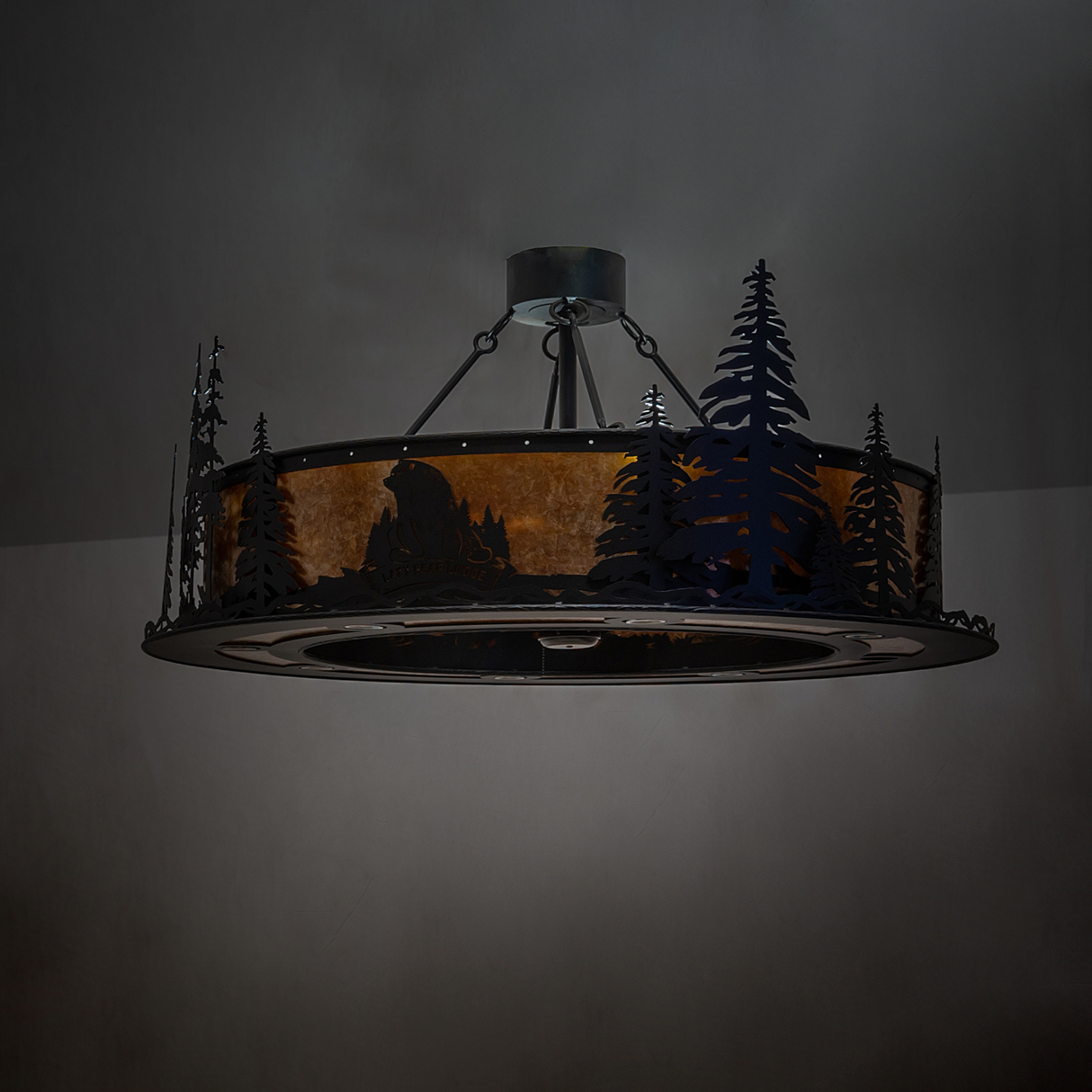 Moody unlit view of Lazy Bear Lodge chandelier highlighting tree design.