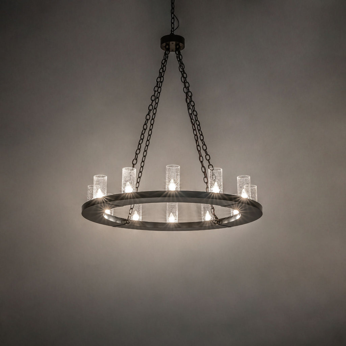 Loxley 12-light bronze chandelier glowing in inside room setting.