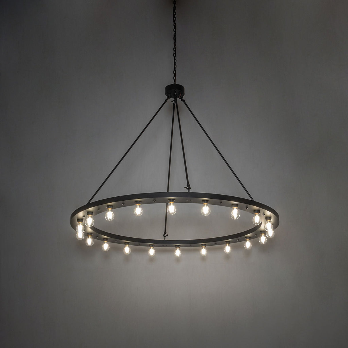 Ambient view of the chandelier casting a warm glow from its circular solar black frame.