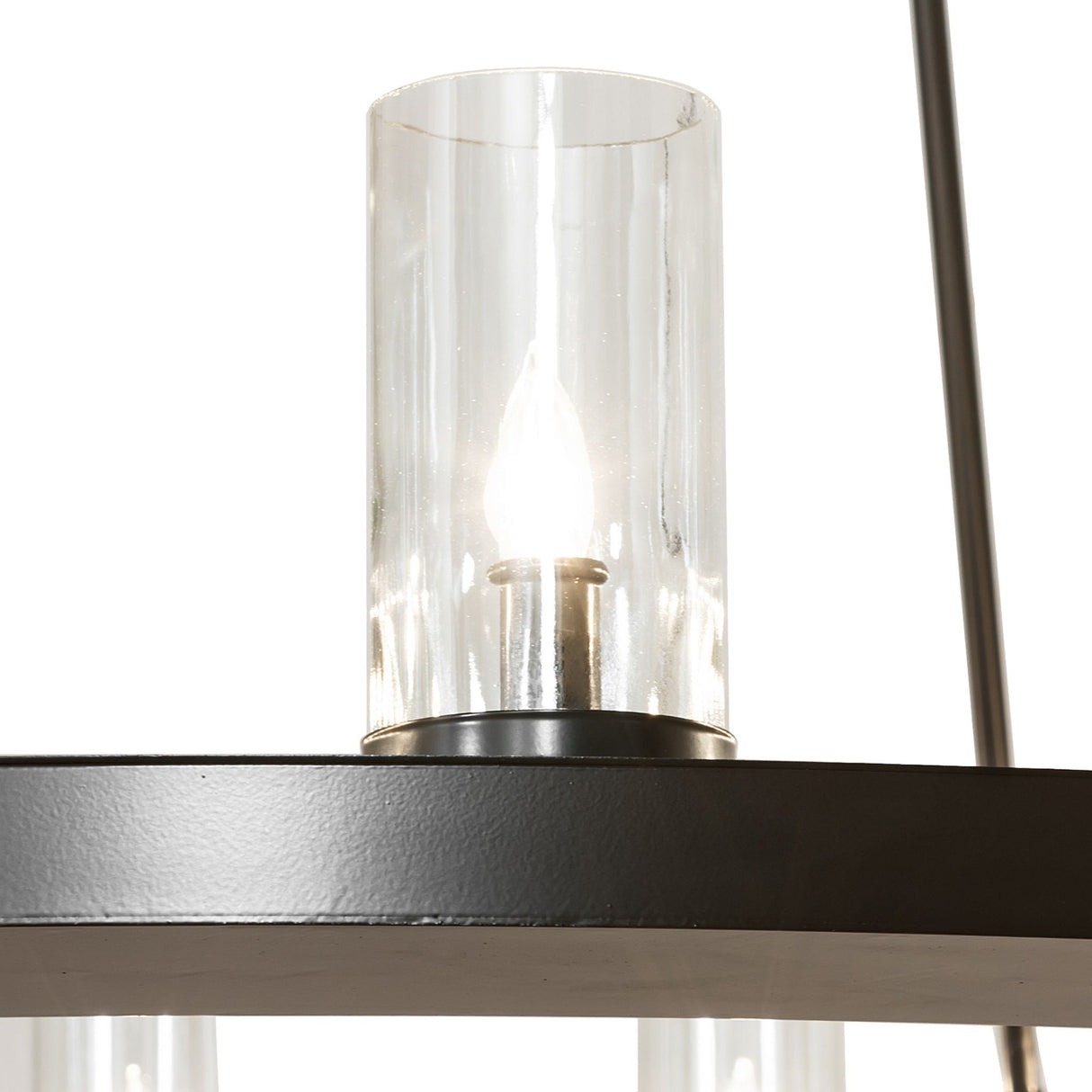 Close-up detail of a clear glass cylinder shade with candle-style bulb on the chandelier.