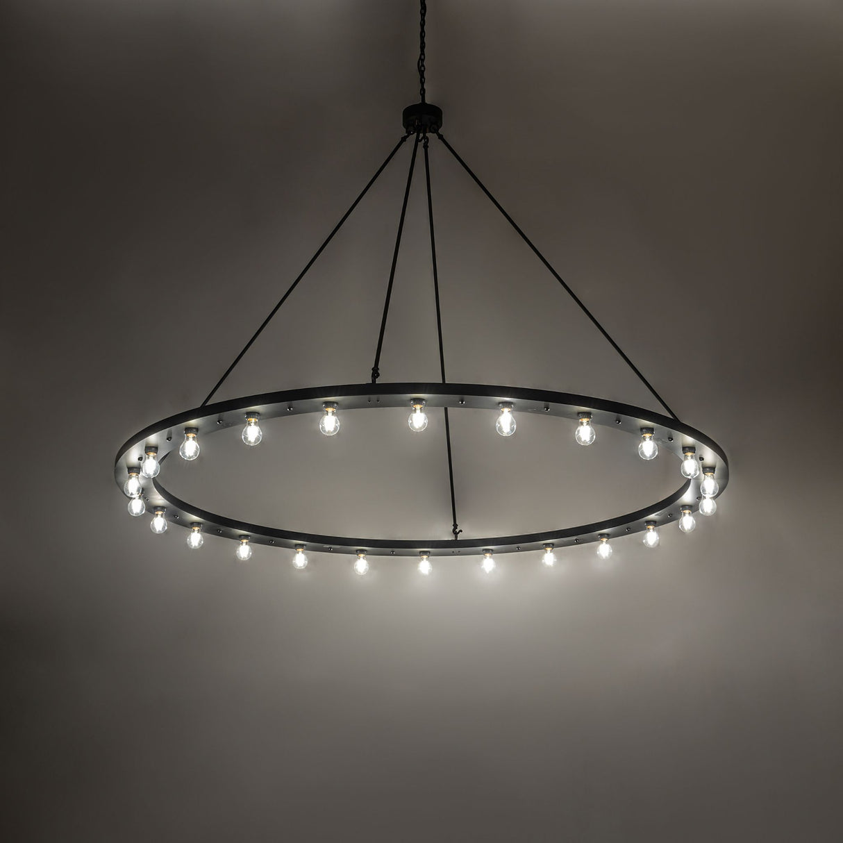Loxley 24-light chandelier illuminated, casting warm ambient light from Edison bulbs.