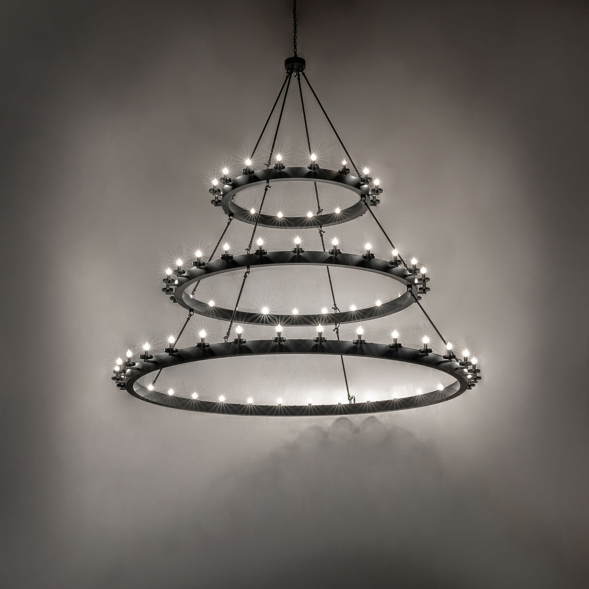 Dark room-lit view of the Loxley three-tier chandelier illuminating the surrounding space.