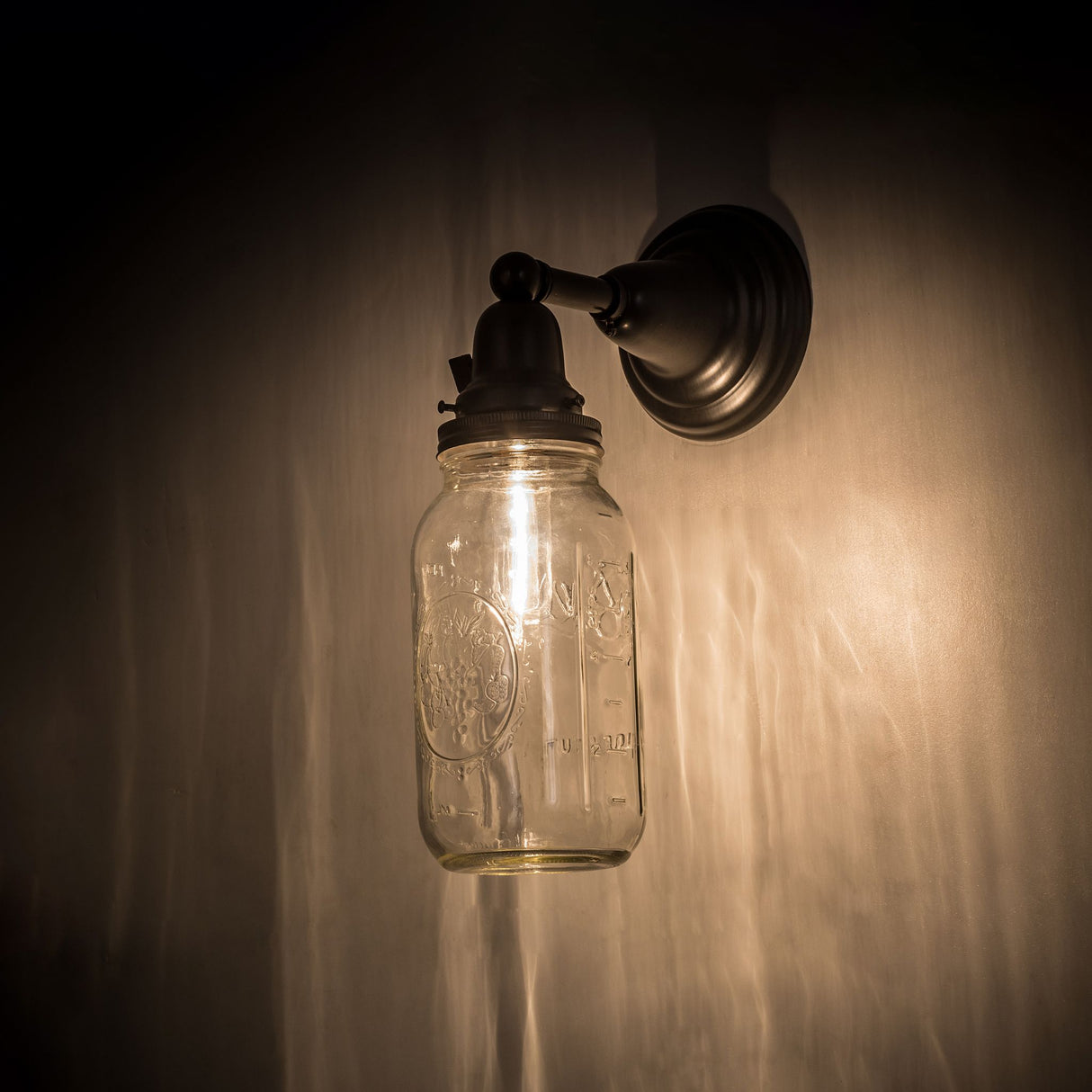Side view of illuminated Mason Jar Wall Sconce casting a soft, warm glow.
