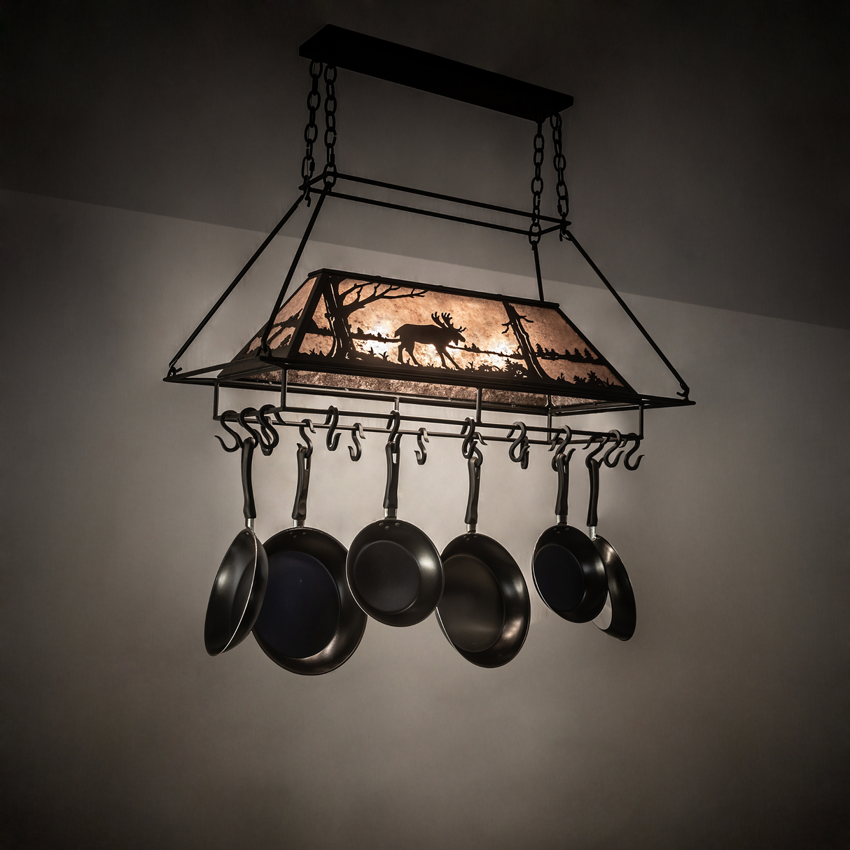 Moose at Lake 3-light pot rack glowing warmly in rustic kitchen setting.