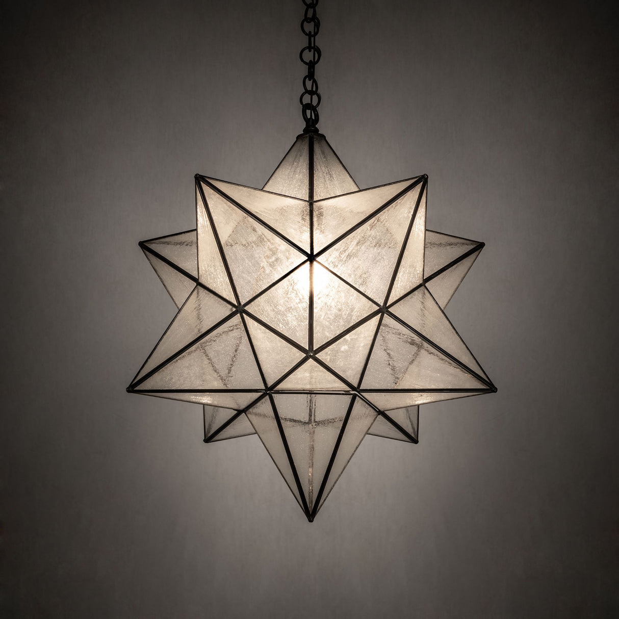 Moravian Star pendant glowing warmly against a dark background.