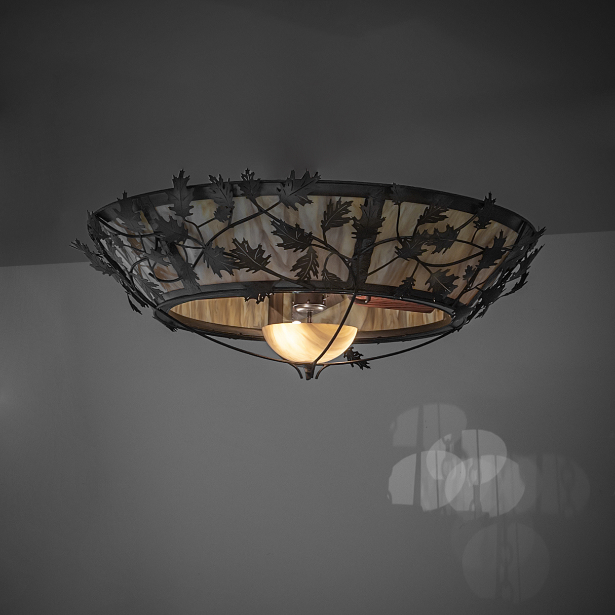 Warm-lit Oak Branch chandelier fan highlighting natural leaf details.