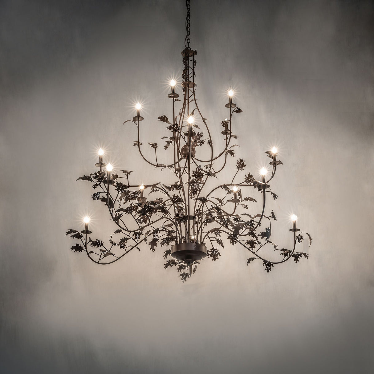 Oak leaf chandelier shown in ambient room setting with warm glowing candle style lights.